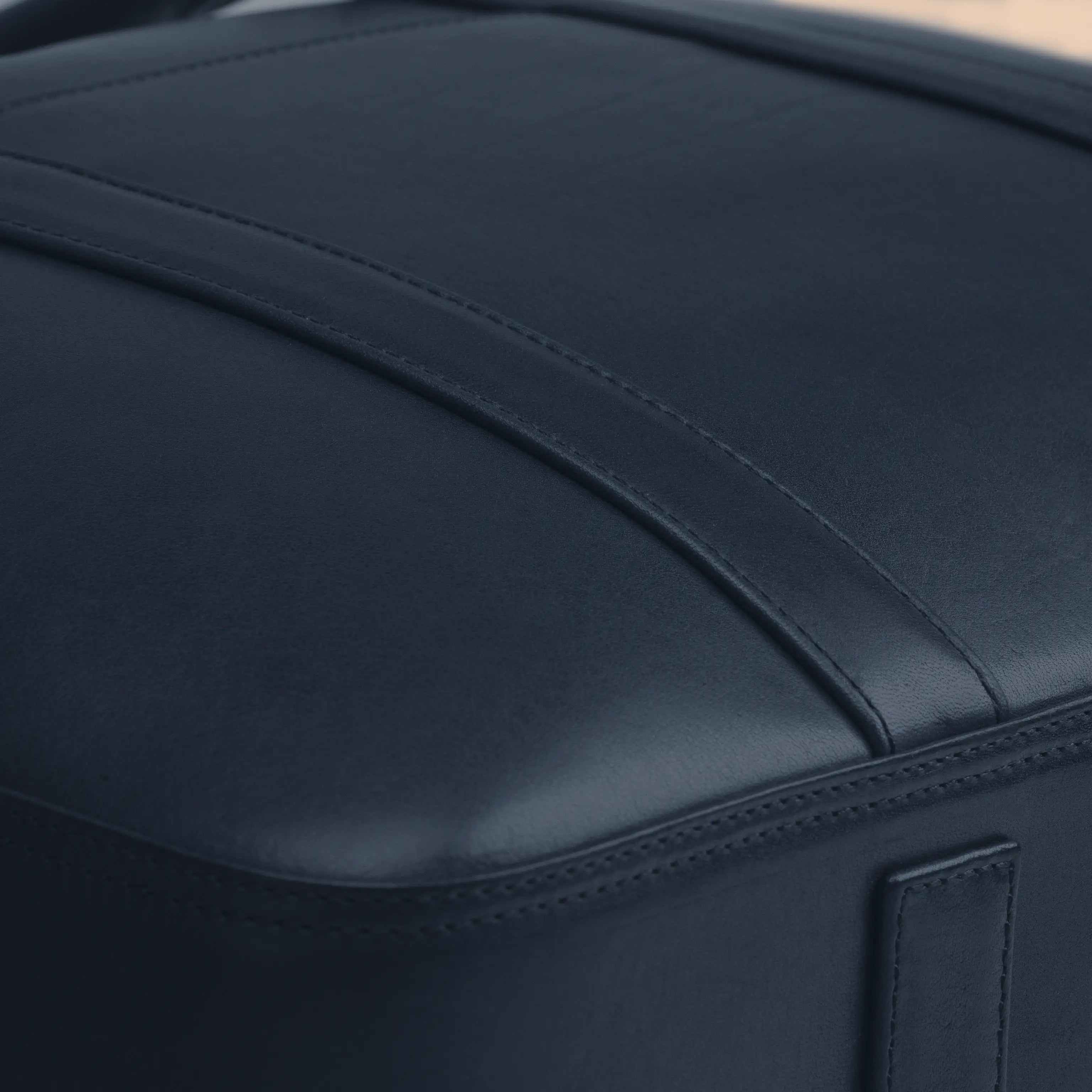 Detail of the Lunburg Opus Briefcase in Nocturnal Sapphire showing the precision panel seam and folded edge construction in vegetable-tanned Perpetual Leather (from Tempesti), precision executed to 0.1 mm tolerance.
