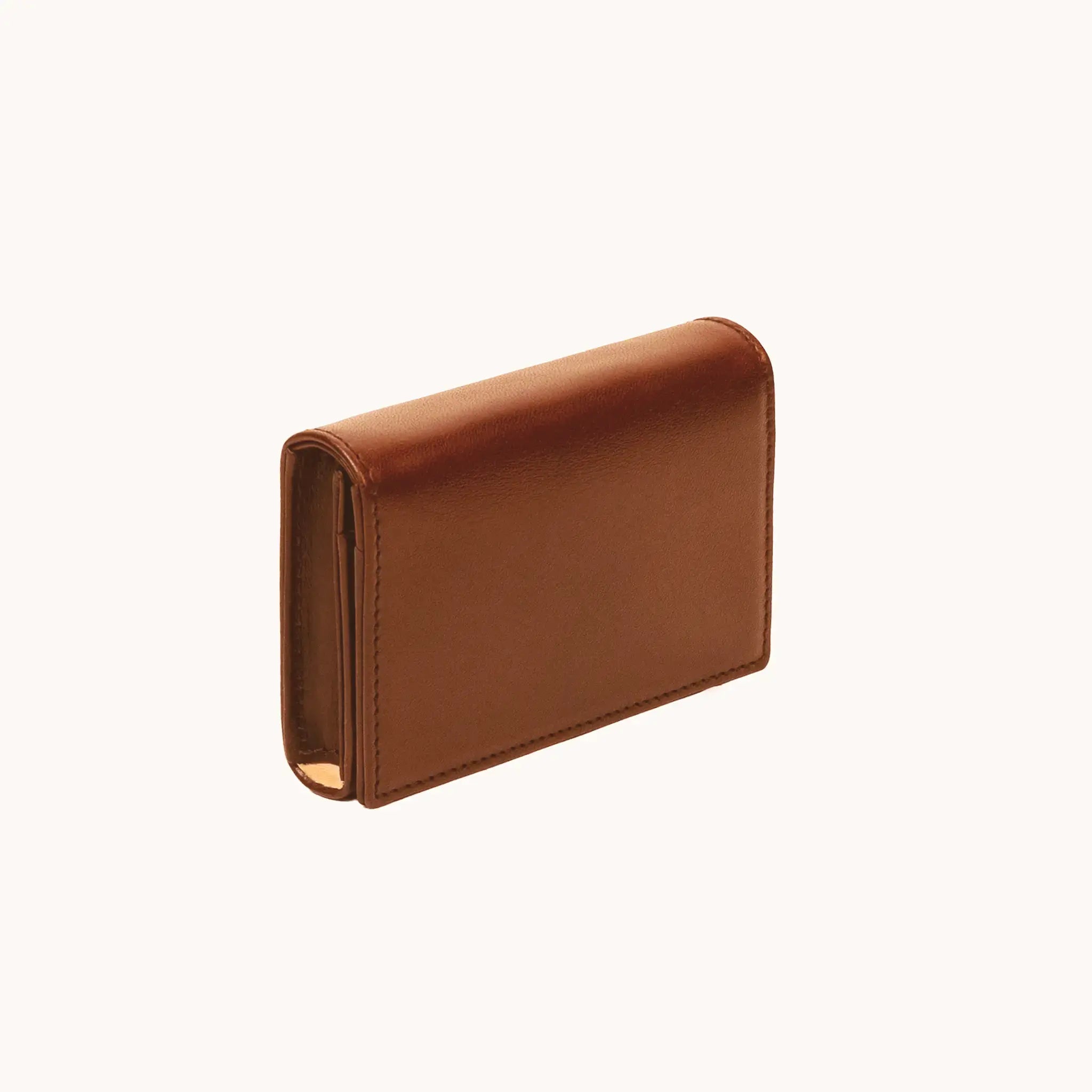Lunburg Signet Business Card Wallet in Heritage Amber, three-quarter view showing the flap closure, spine, and a glimpse of the goat leather lining interior, in vegetable-tanned Perpetual Leather (from Tempesti) with folded edge construction.