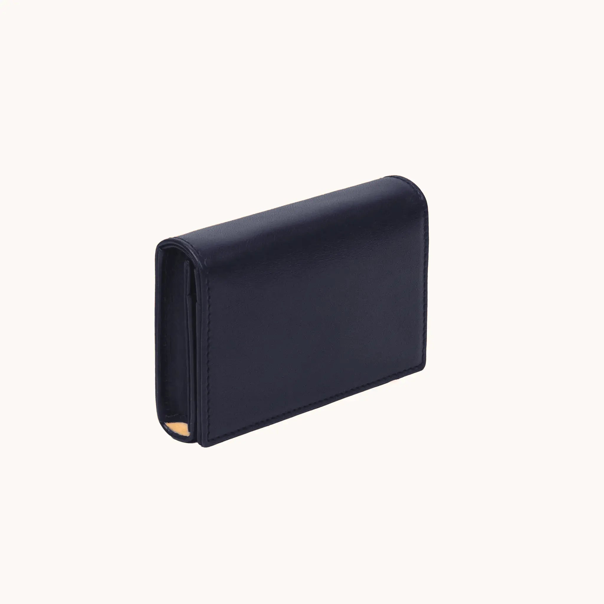 Lunburg Signet Business Card Wallet in Nocturnal Sapphire, three-quarter view showing the flap closure, spine, and a glimpse of the goat leather lining interior, in vegetable-tanned Perpetual Leather (from Tempesti) with folded edge construction.