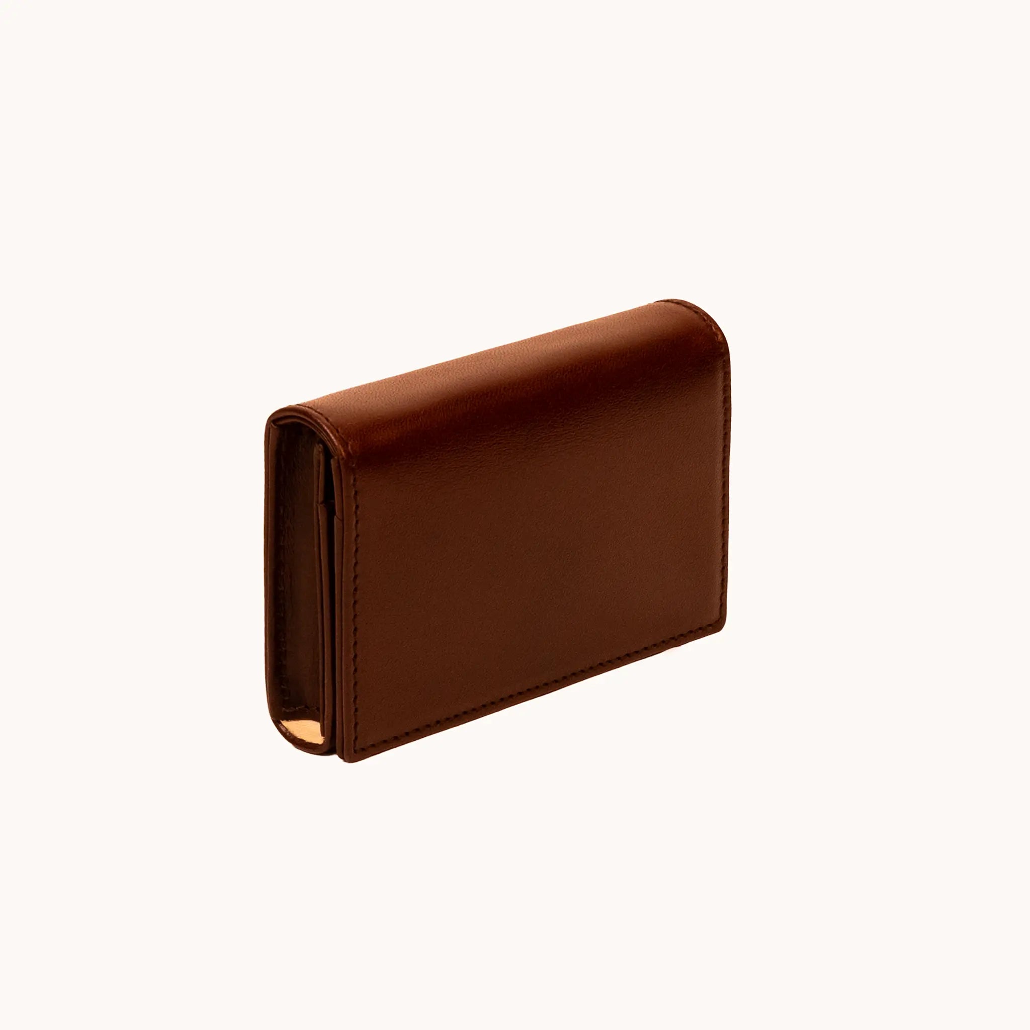 Lunburg Signet Business Card Wallet in Deep Mahogany, three-quarter view showing the flap closure, spine, and a glimpse of the goat leather lining interior, in vegetable-tanned Perpetual Leather (from Tempesti) with folded edge construction.