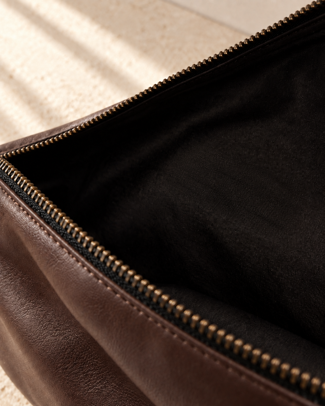 Interior detail of the illustrative crescent bag showing metal zip teeth, dark woven lining and leather-looking mouth facing.