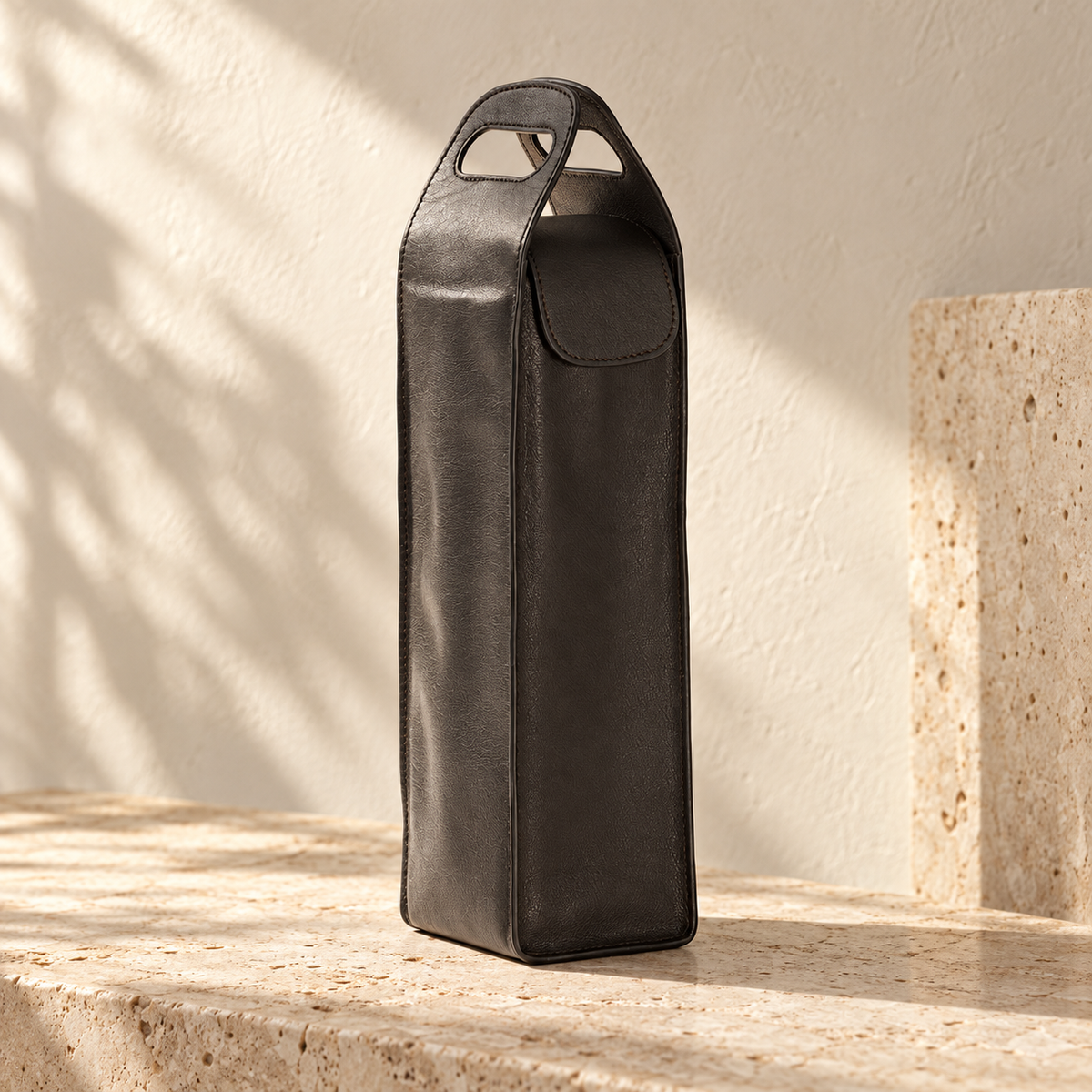 Illustrative cutout-handle bottle carrier, view 1: tall narrow carrier with paired cutout handles, stitched edges and a rounded front flap.