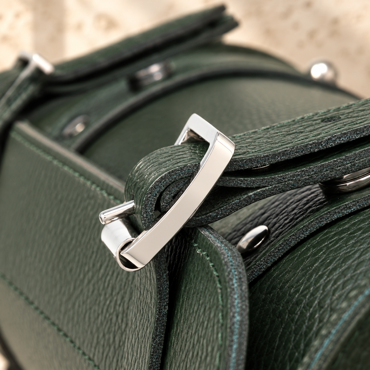 Close detail of the illustrative cylindrical handbag showing round release fittings beneath a buckle-look strap.