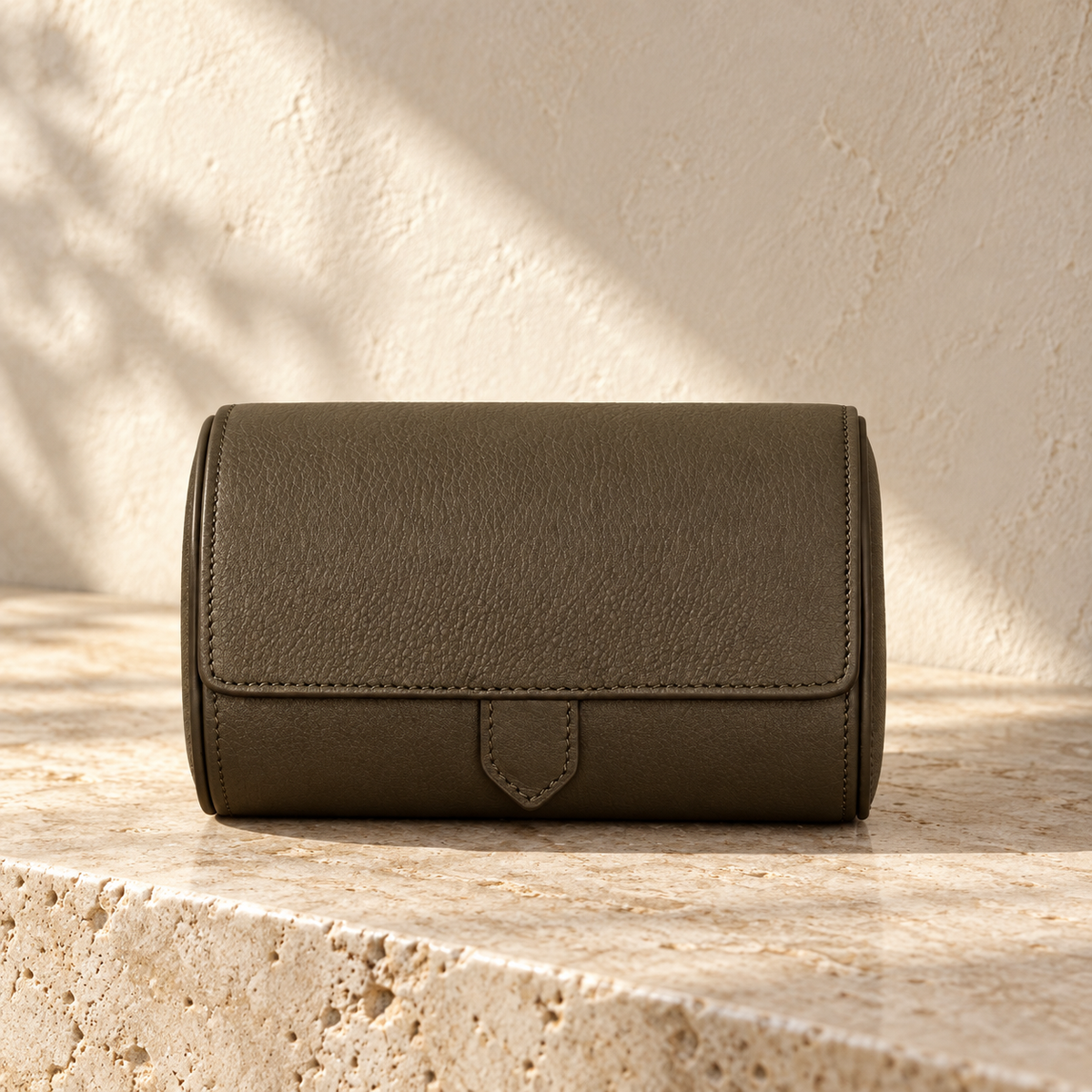 Illustrative divided two-cushion watch roll, view 1: closed curved case with stitched front flap and central pointed tab.