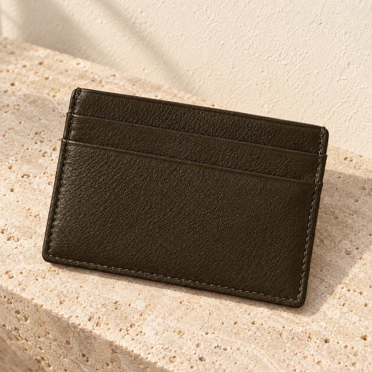 Illustrative flat pocket cardholder — flat dark cardholder with two stacked exterior pocket mouths on the shown face and stitched sides/lower edge.