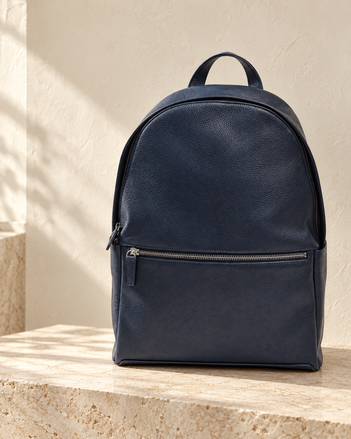 Illustrative front-pocket zip daypack with a rounded top, curved main zip and projecting front zipped pocket.