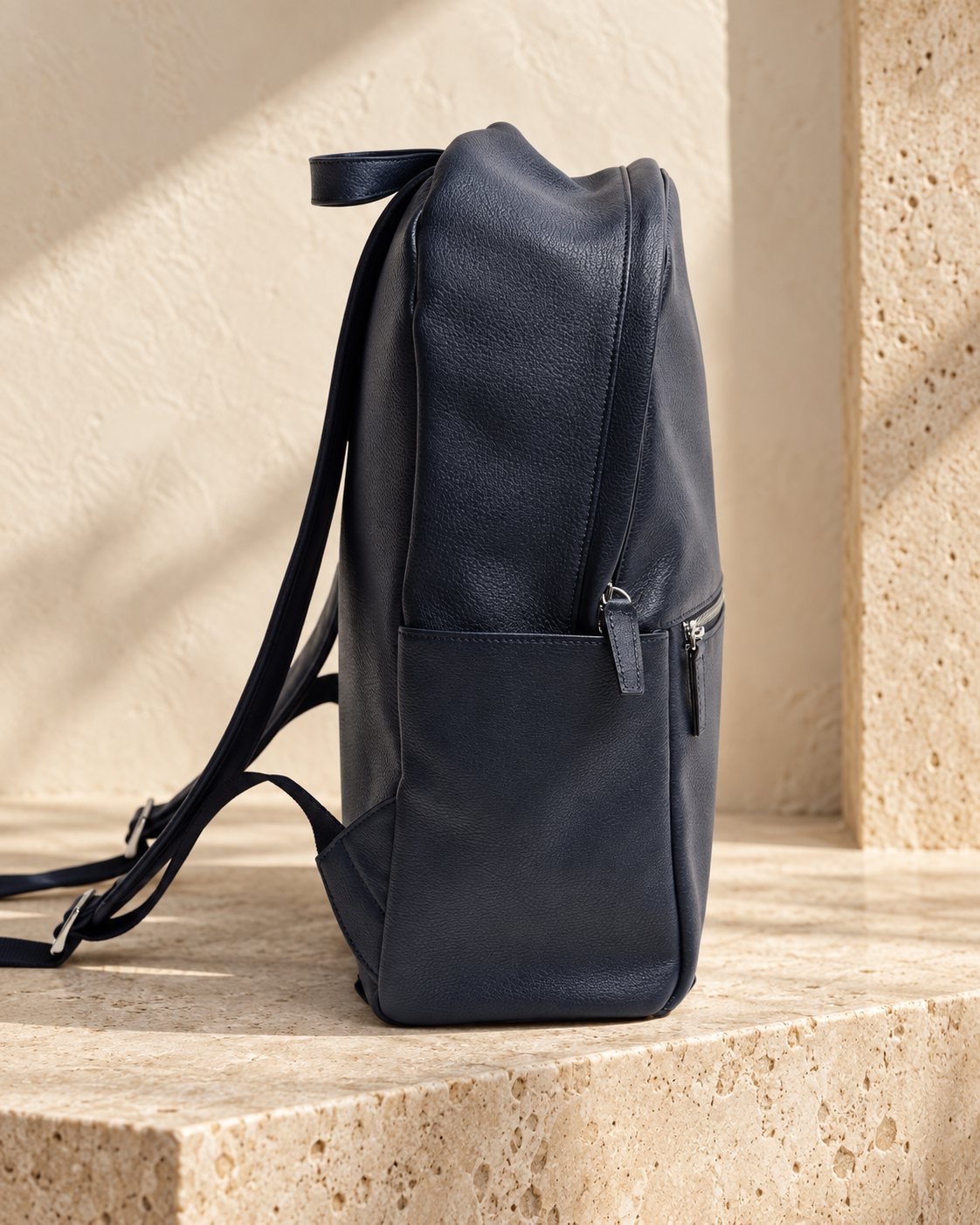 Side view of the illustrative daypack showing the side slip pocket, top carry loop and rear straps.