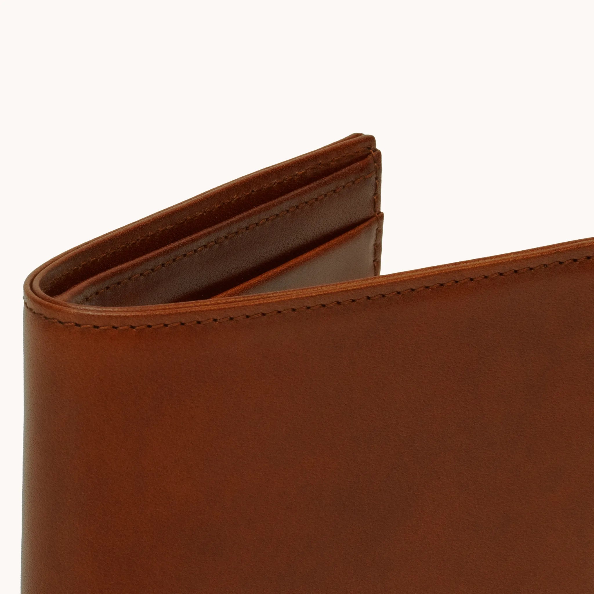 Lunburg Signet Horizontal Bifold in Deep Mahogany, close-up detail of the spine and upper card slot edges showing the folded edge construction of Rempliage where no raw edges are visible, in vegetable-tanned Perpetual Leather (from Tempesti).