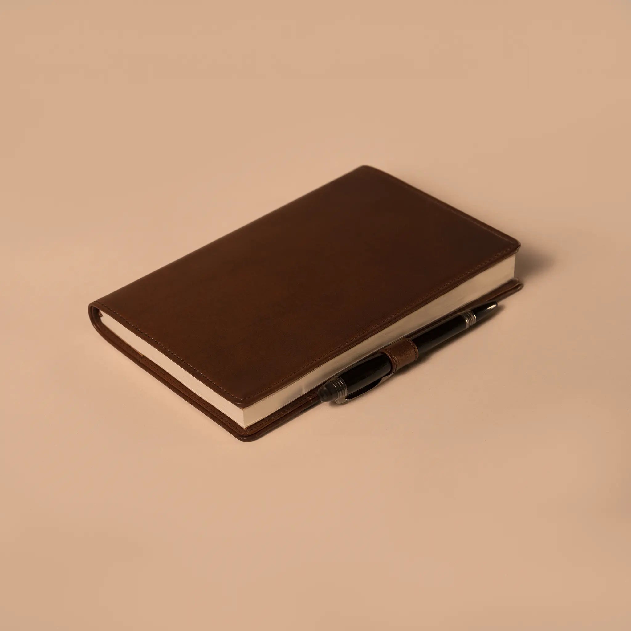 Lunburg Memoir Notebook Cover with Pen Loop in Deep Mahogany, close-up detail of the leather pen loop holding a pen along the spine, showing the folded edge construction and page block, in vegetable-tanned Perpetual Leather (from Tempesti).