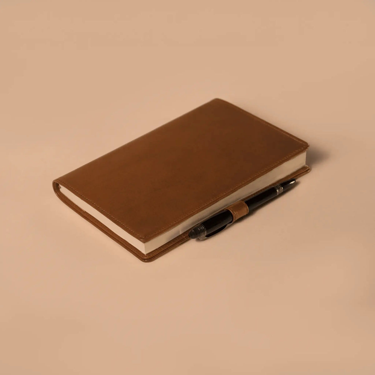 Lunburg Memoir Notebook Cover with Pen Loop in Heritage Amber, close-up detail of the leather pen loop holding a pen along the spine, showing the folded edge construction and page block, in vegetable-tanned Perpetual Leather (from Tempesti).