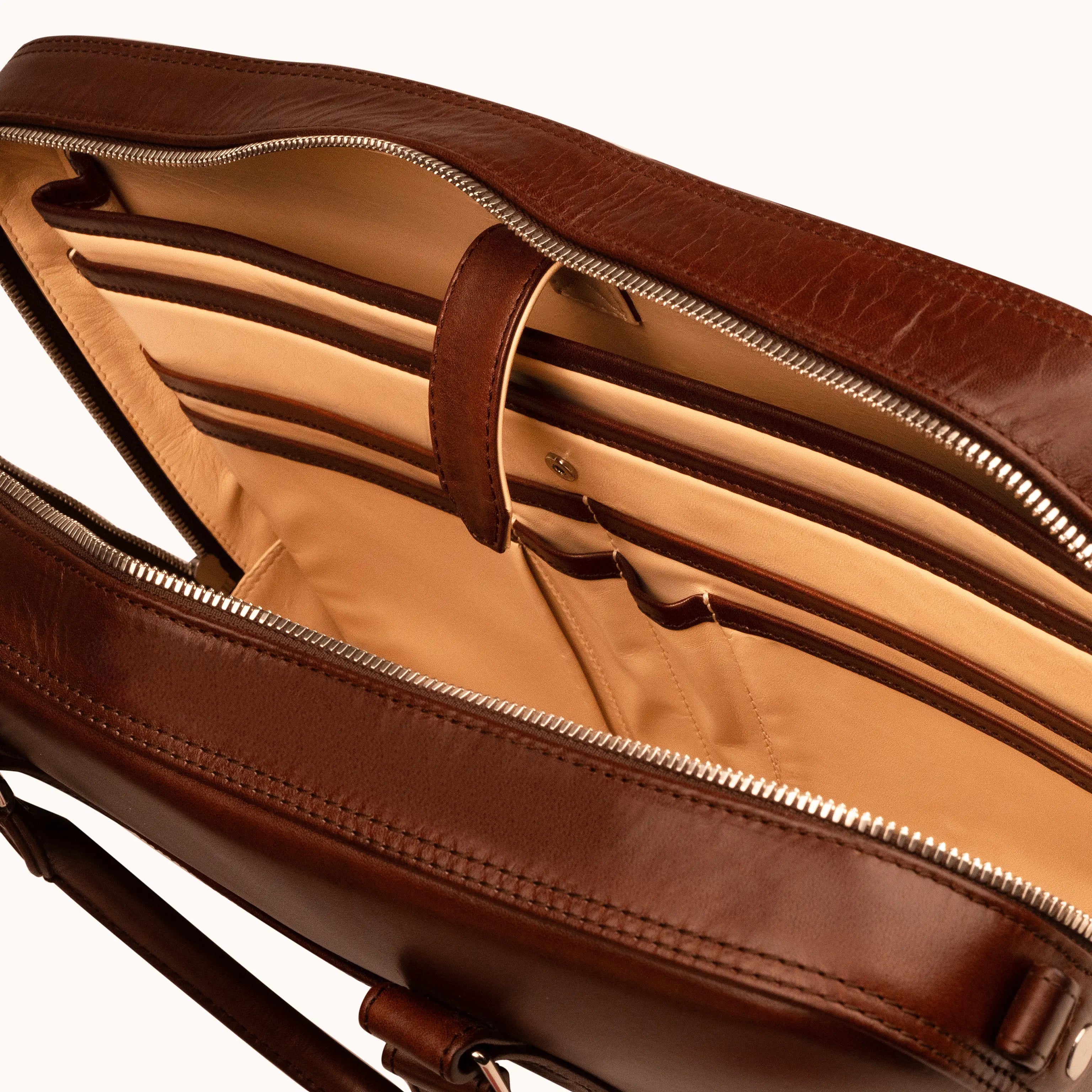 Lunburg Opus Briefcase in Deep Mahogany opened from above, revealing multiple compartments, padded laptop divider, tablet compartment, goat leather lining, leather handle strap, and 316L stainless steel hardware, in vegetable-tanned Perpetual Leather exterior with folded edge construction.