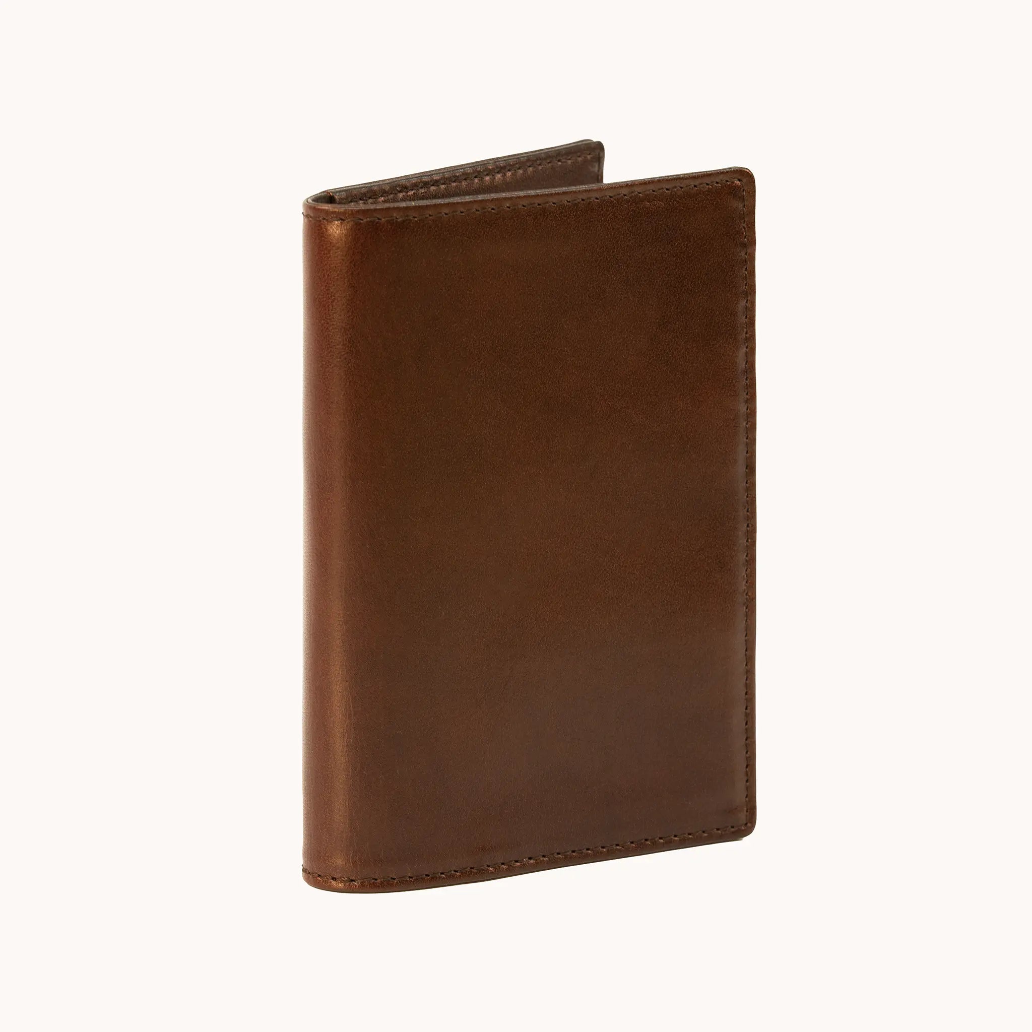 Lunburg Signet Passport Folio in Deep Mahogany, three-quarter view slightly open showing the exterior grain, spine, and a glimpse of the interior, in vegetable-tanned Perpetual Leather (from Tempesti) with folded edge construction.