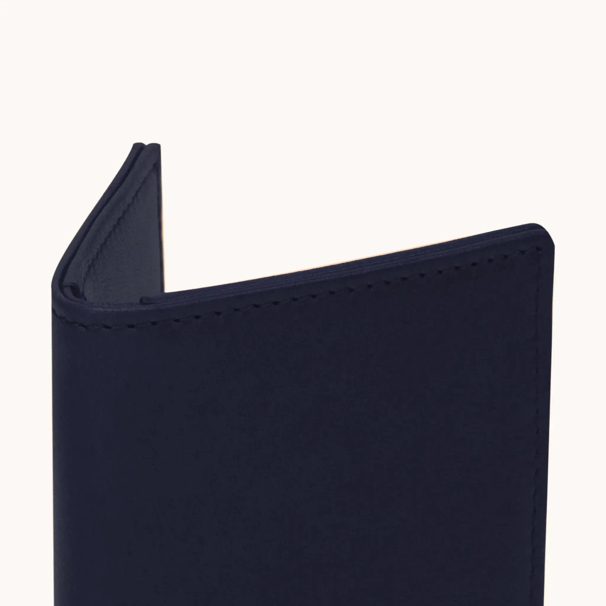 Lunburg Signet Passport Folio in Nocturnal Sapphire, close-up detail of the spine and upper edge showing the folded edge construction of Rempliage where no raw edges are visible, in vegetable-tanned Perpetual Leather (from Tempesti).