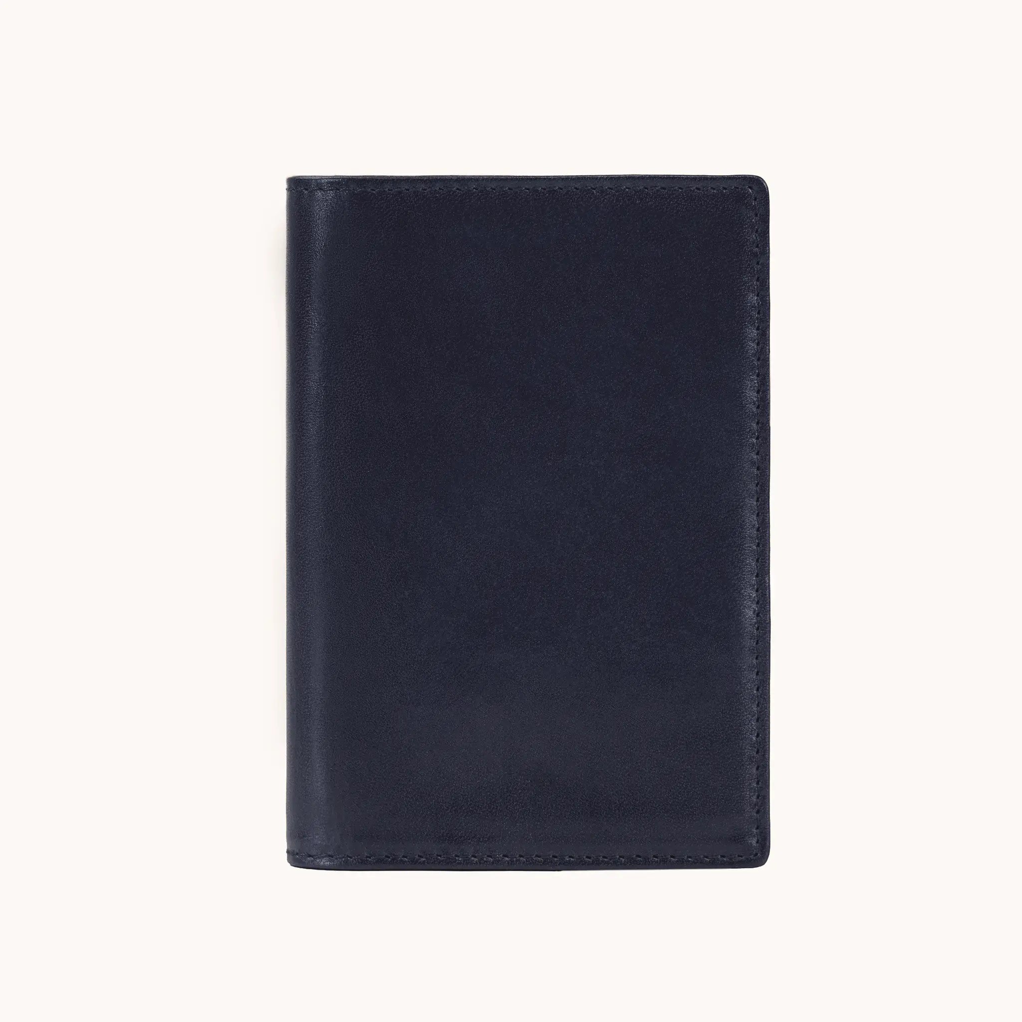 Lunburg Signet Passport Folio in Nocturnal Sapphire, front view closed, showing the clean face of vegetable-tanned Perpetual Leather (from Tempesti) with folded edge construction and no visible raw edges.