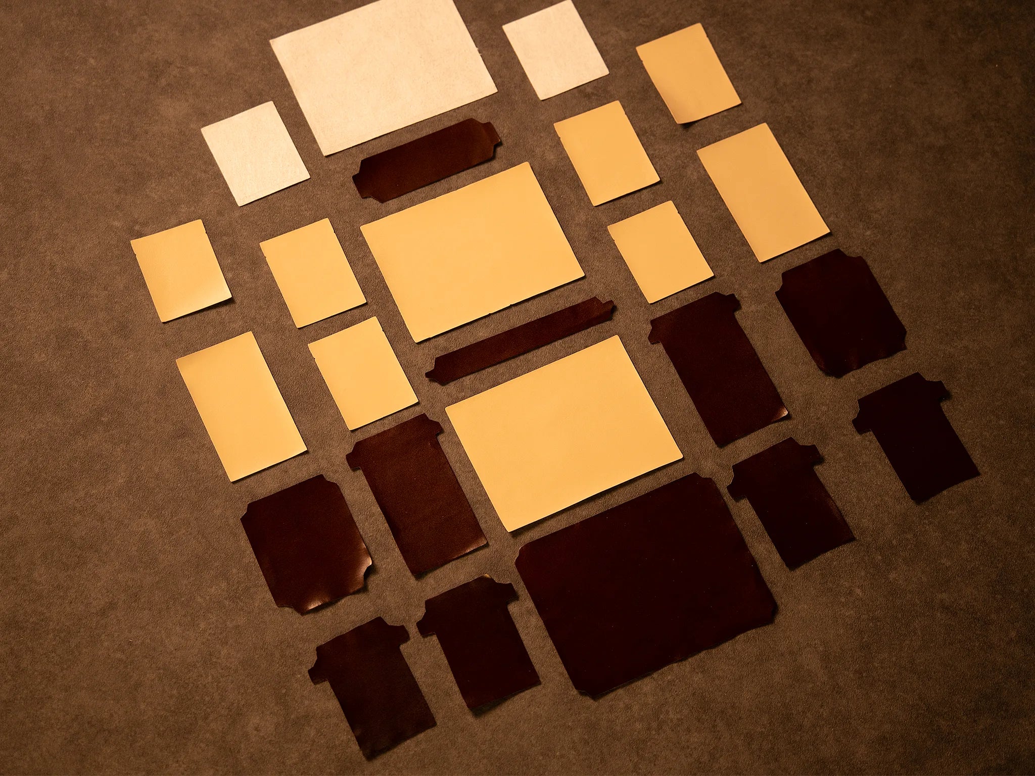 Over twenty individual panels of vegetable-tanned Leather laid out on a work surface in the Fes atelier, each cut and prepared by hand to 0.1 mm precision before being united through Rempliage into a single Signet wallet.