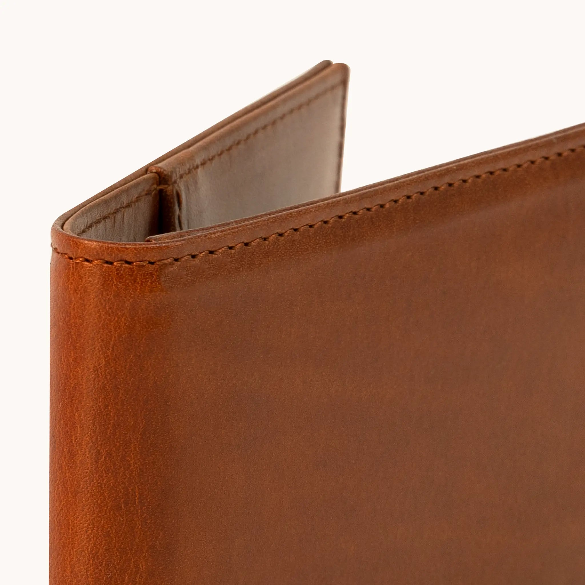 Close-up of the upper spine and fold of the Lunburg Small Horizontal Signet Wallet in Heritage Amber, showing folded edge construction, edge stitching, and interior glimpse in vegetable-tanned Perpetual Leather.