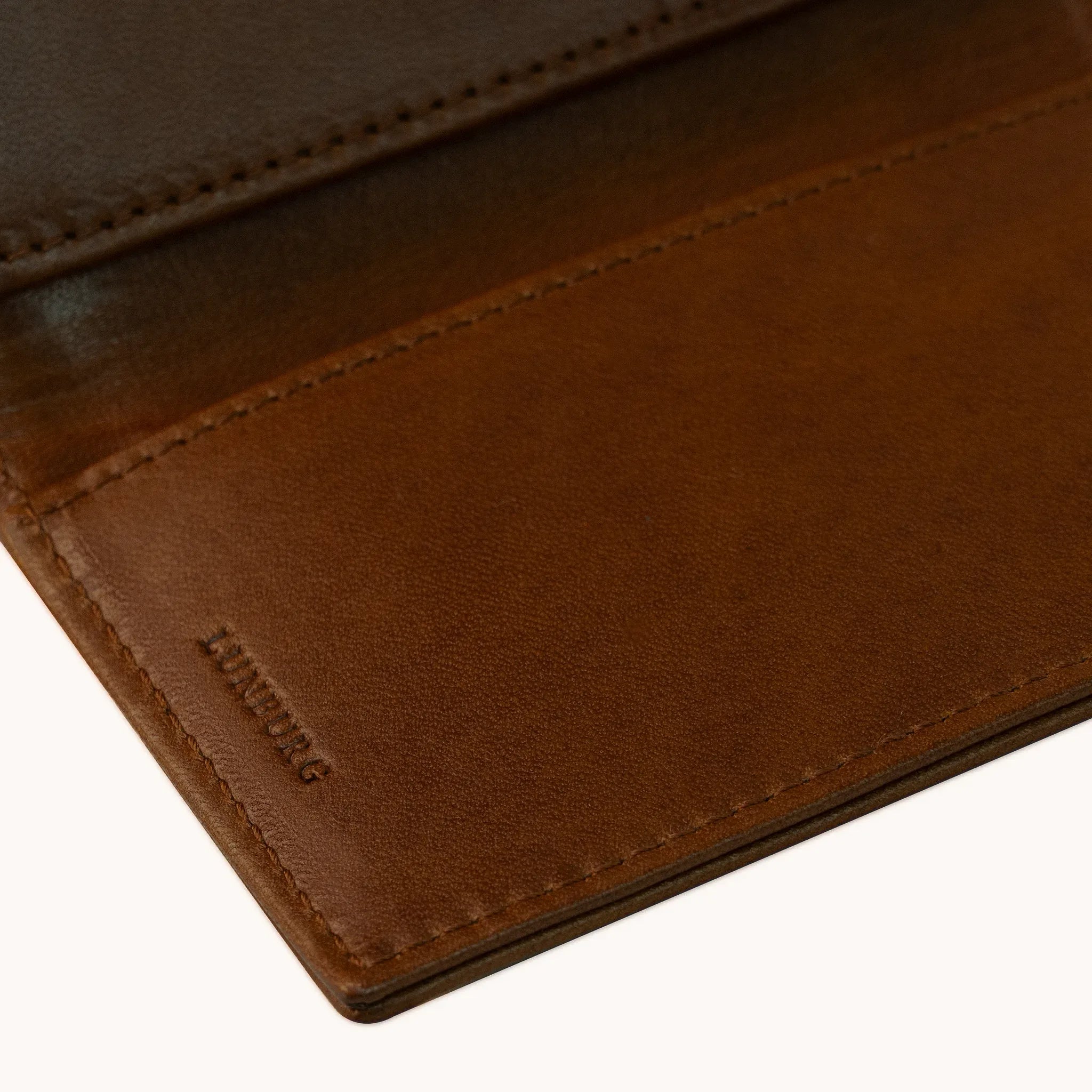 Lunburg Signet Small Vertical in Deep Mahogany, detail view of the interior lower panel showing the heat-embossed Lunburg mark beneath card slots, in vegetable-tanned Perpetual Leather (from Tempesti) with folded edge construction throughout.