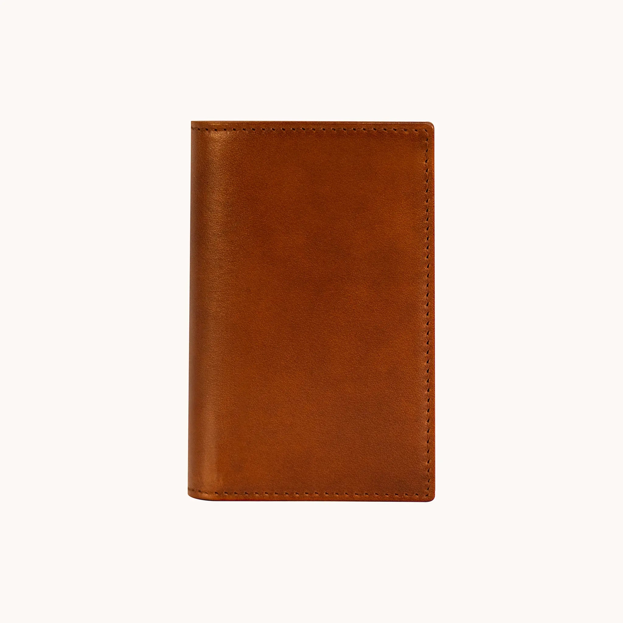 Lunburg Small Vertical Signet Wallet in Heritage Amber, closed front view showing the uninterrupted leather surface, folded edge construction, natural color variation, and perimeter stitching in vegetable-tanned Perpetual Leather.