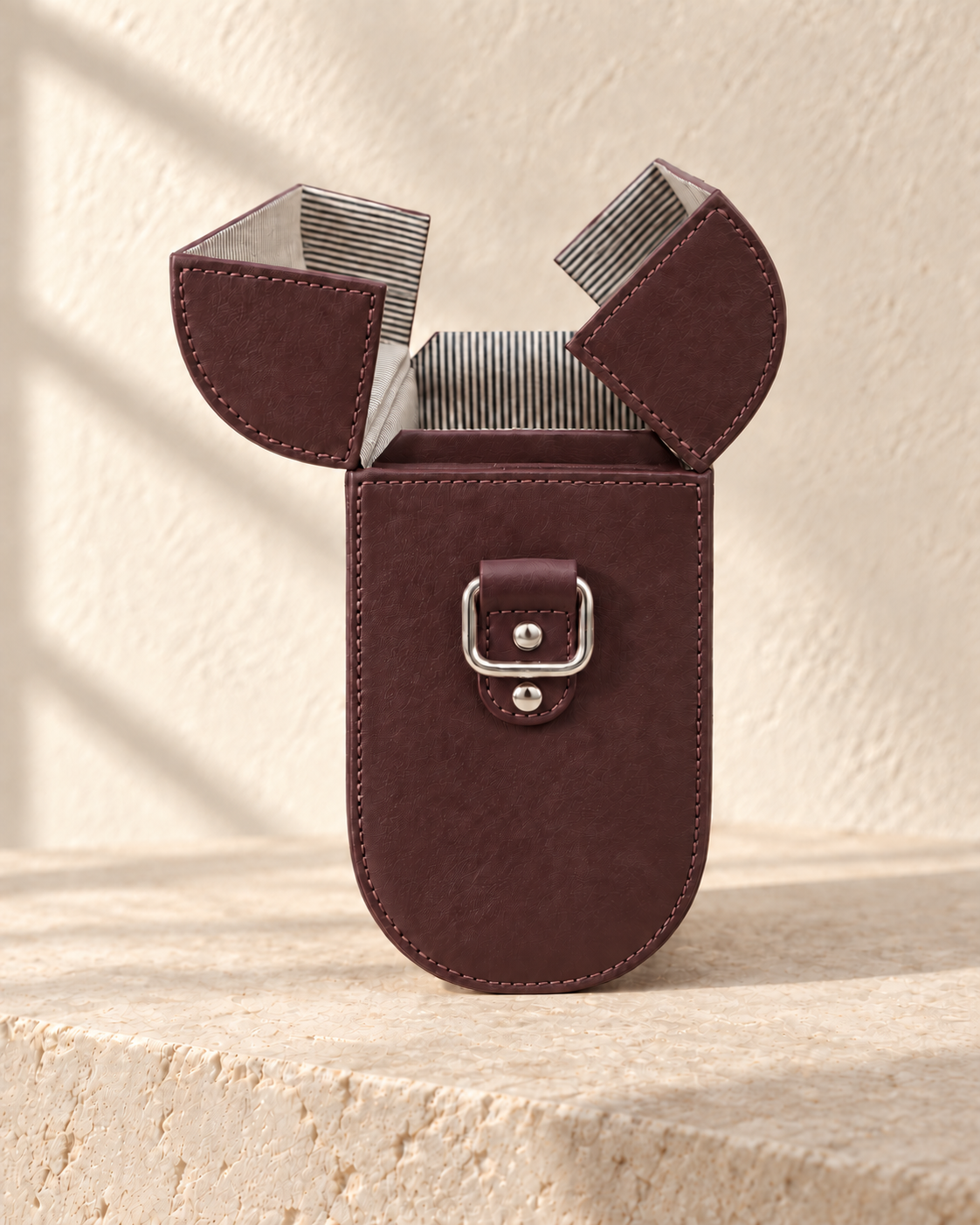 Open view of the illustrative box crossbody with two curved top flaps opening apart and striped textile-look reverse surfaces.