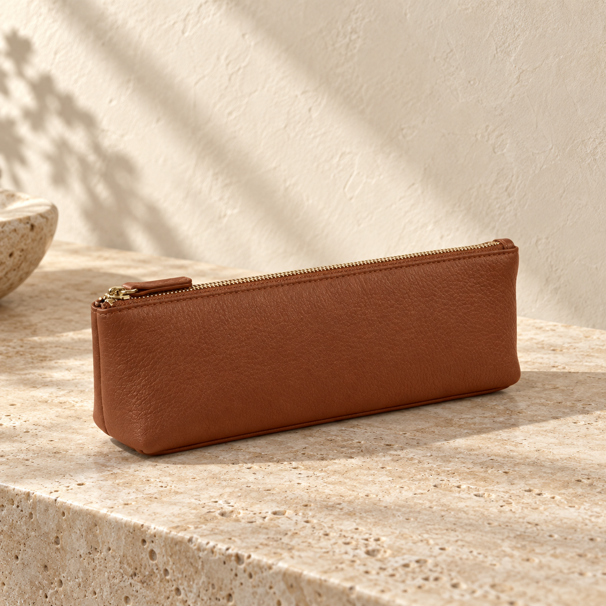 Illustrative standing zip pencil pouch — long narrow brown zip pouch with a flat standing base, rounded end corners and visible stitch line along the zip.