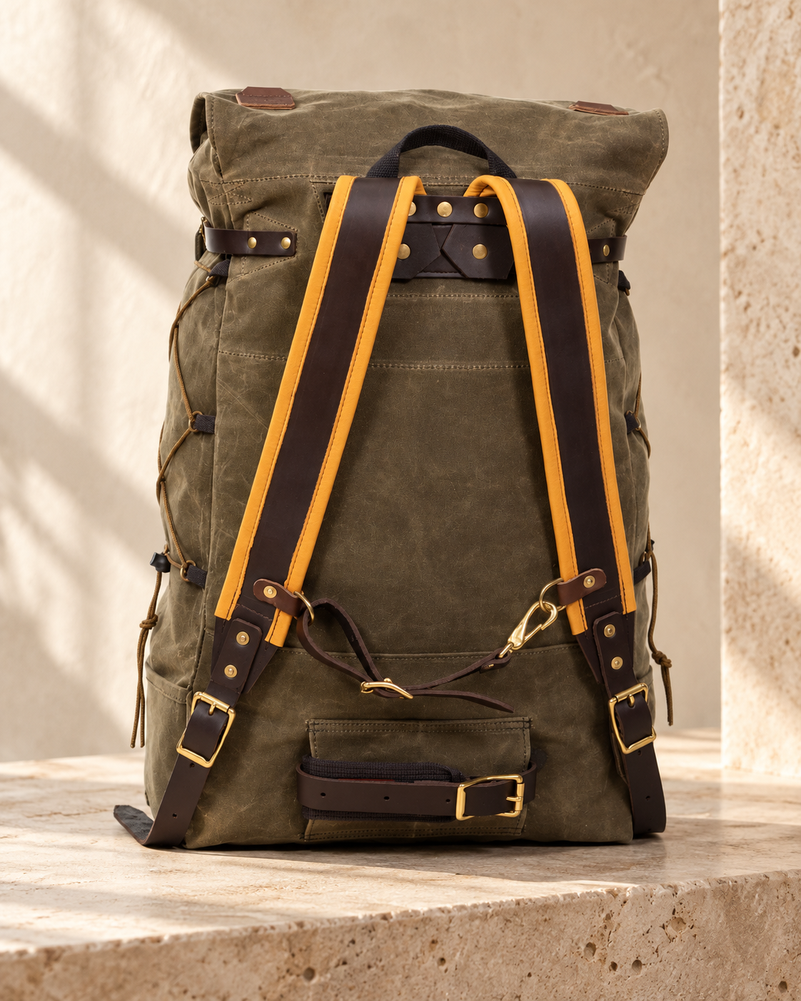 Rear view of the illustrative textile-body buckle backpack showing a broad shoulder harness, chest connector and rolled lower belt.