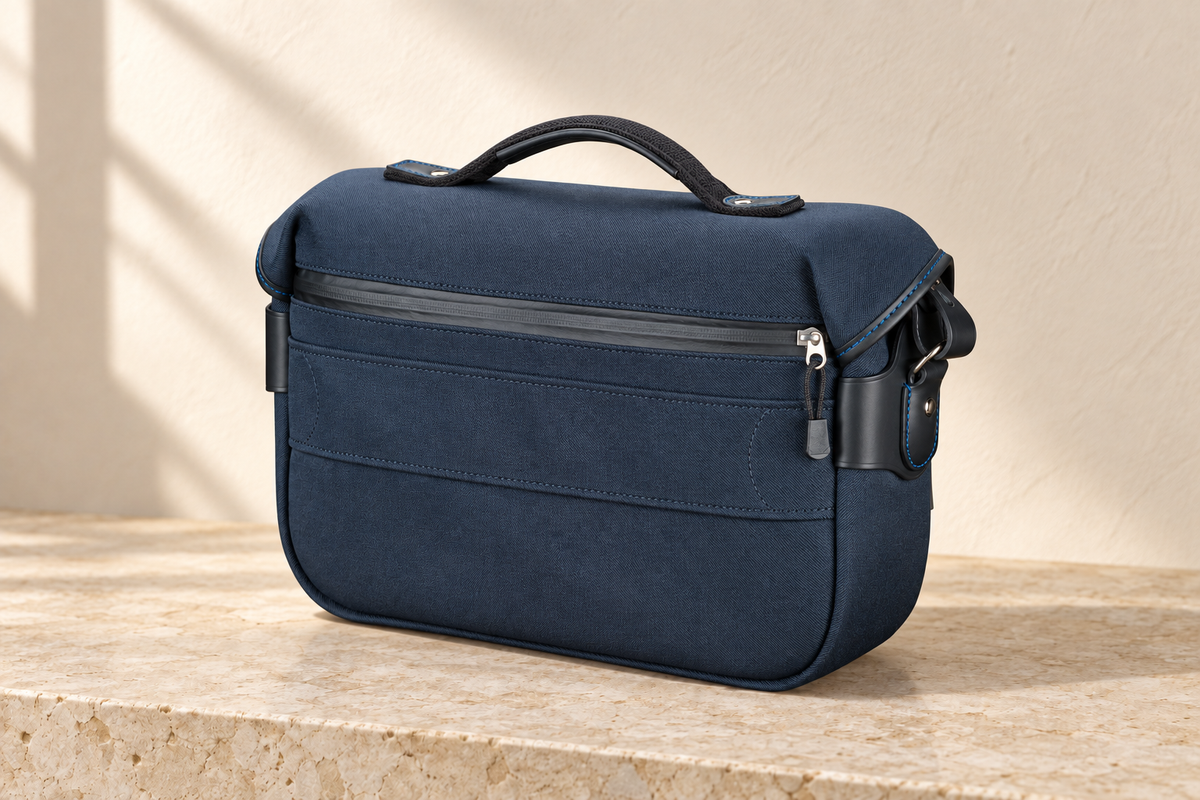 Rear of the illustrative textile-body equipment bag showing a wide zip pocket, horizontal band, handle roots and bound side perimeter.