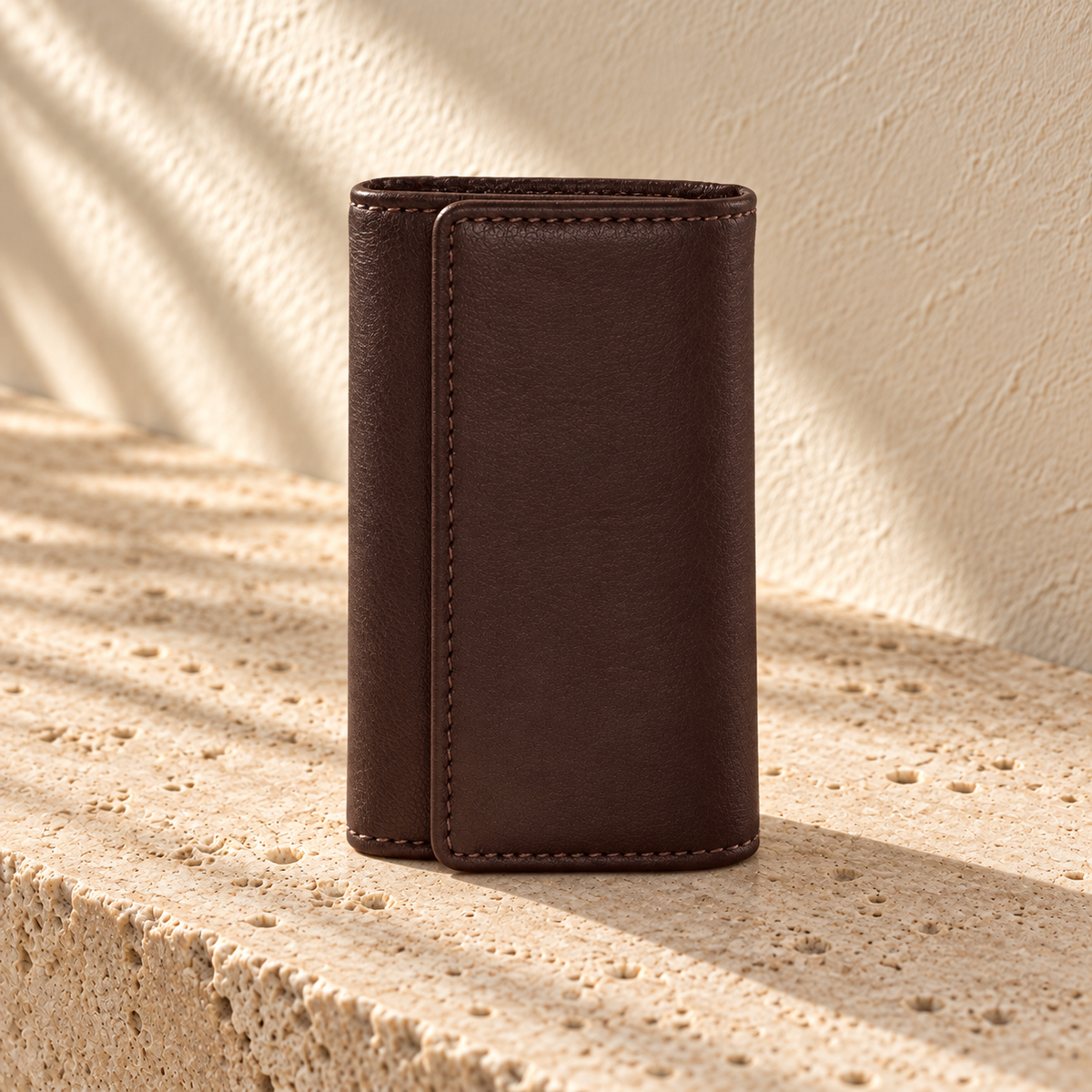 Upright view of the illustrative trifold key case showing the plain outer flap and rounded fold edges.