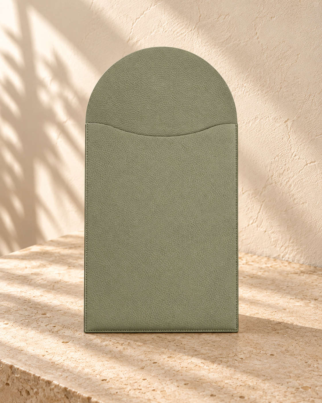 Illustrative unfolding work-surface sleeve — rounded flap extends above a shallow concave pocket mouth; fine pebbling and perimeter stitches visible.