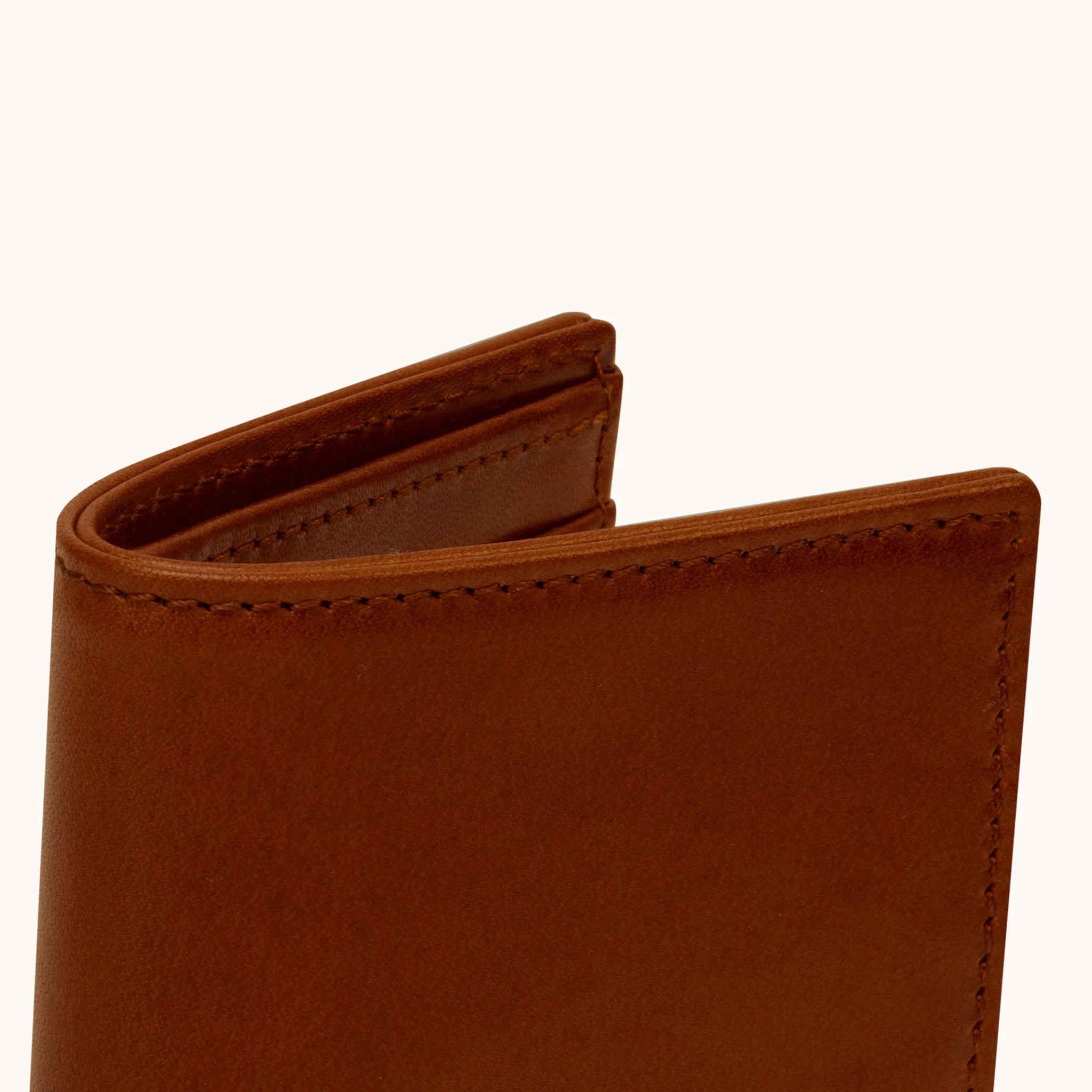 Lunburg Signet Vertical Bifold in Deep Mahogany, close-up detail of the spine and upper card slot edges showing the folded edge construction of Rempliage where no raw edges are visible, in vegetable-tanned Perpetual Leather (from Tempesti).