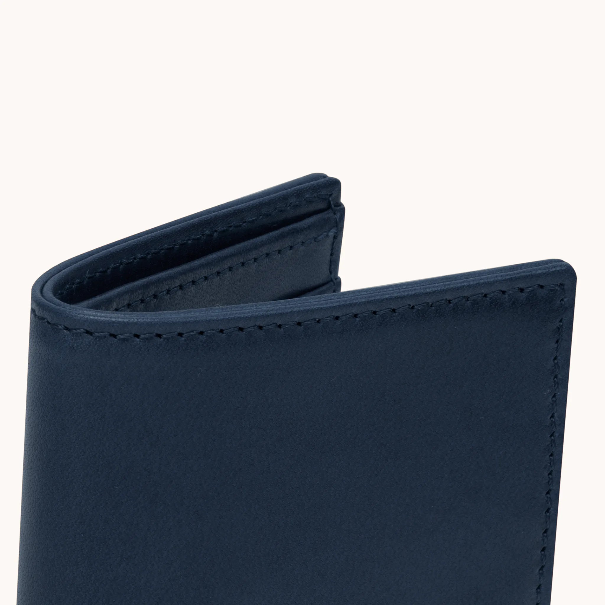 Lunburg Signet Vertical Bifold in Nocturnal Sapphire, close-up detail of the spine and upper card slot edges showing the folded edge construction of Rempliage where no raw edges are visible, in vegetable-tanned Perpetual Leather (from Tempesti).