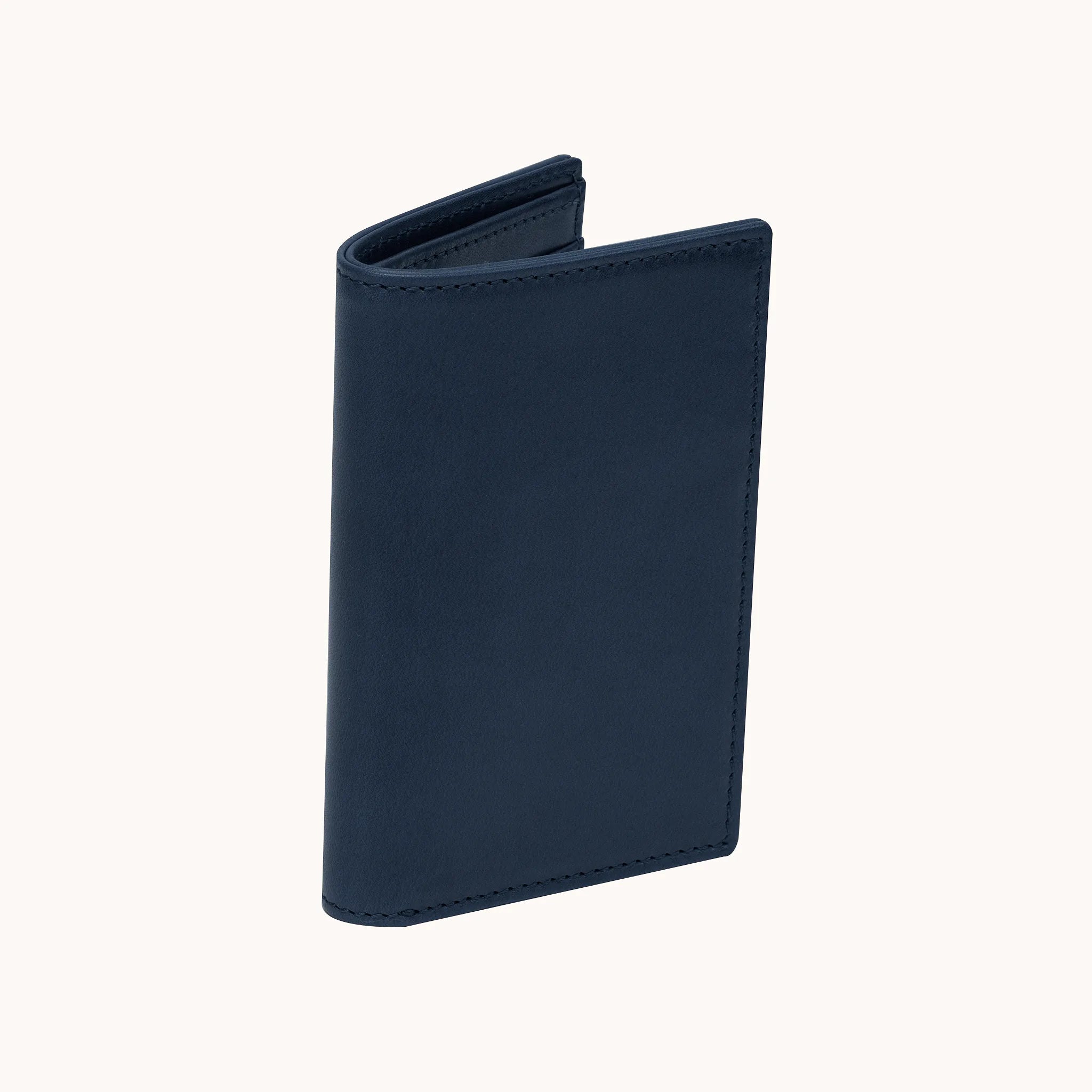 Lunburg Signet Vertical Bifold in Nocturnal Sapphire, three-quarter view slightly open showing the exterior grain, spine, and a glimpse of the interior, in vegetable-tanned Perpetual Leather (from Tempesti) with folded edge construction.