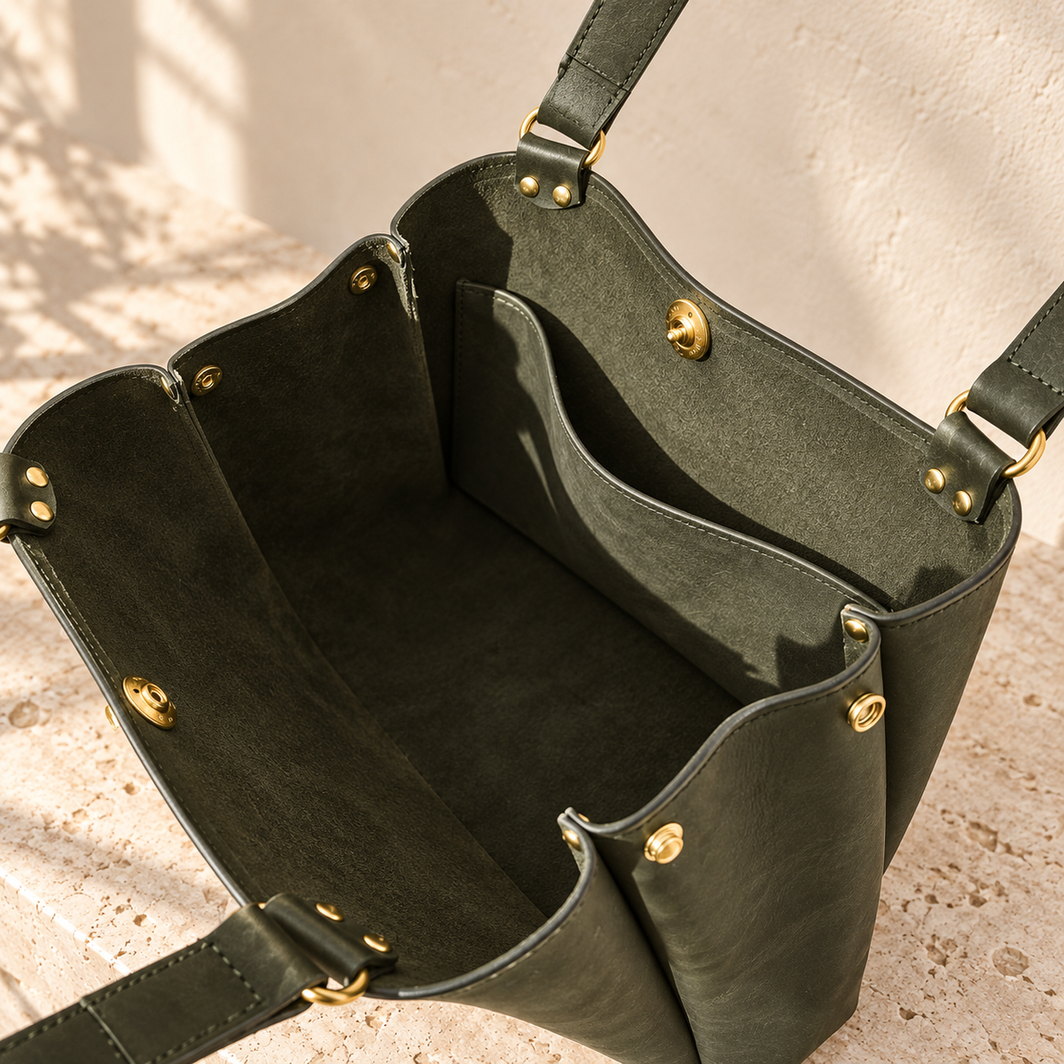 Open detail of the illustrative wing-gusset tote with snap fittings, a suede-like interior and broad hanging slip pocket.