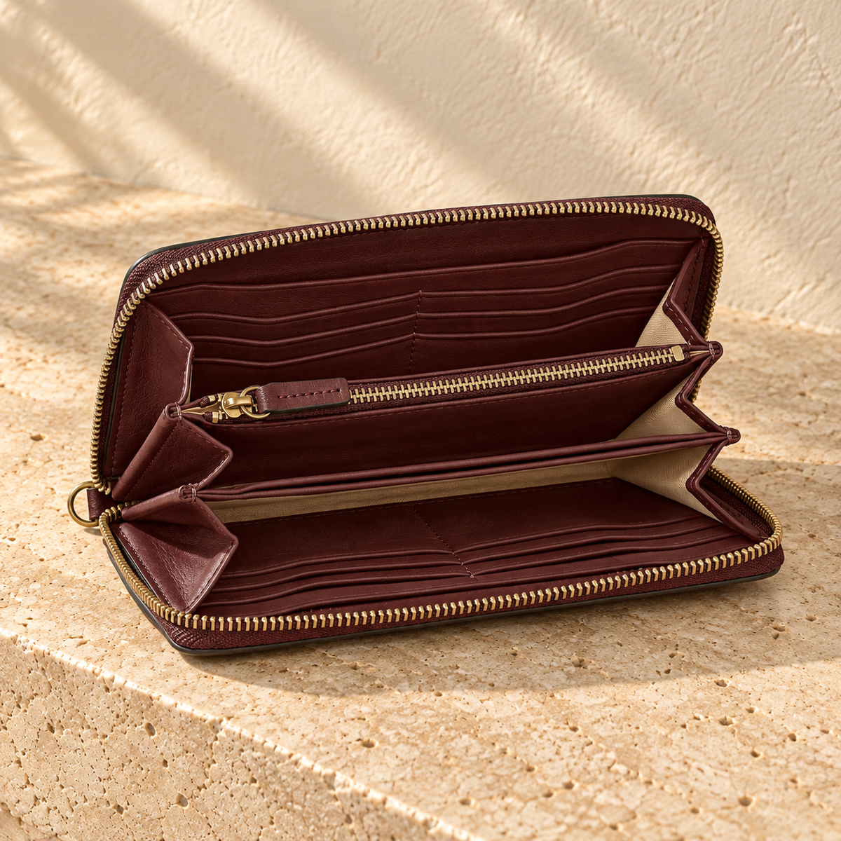 Illustrative zip-around divided wallet — open view shows opposed tiered card banks, accordion side gussets, central zipped partition, another flat divider and pale interior areas.