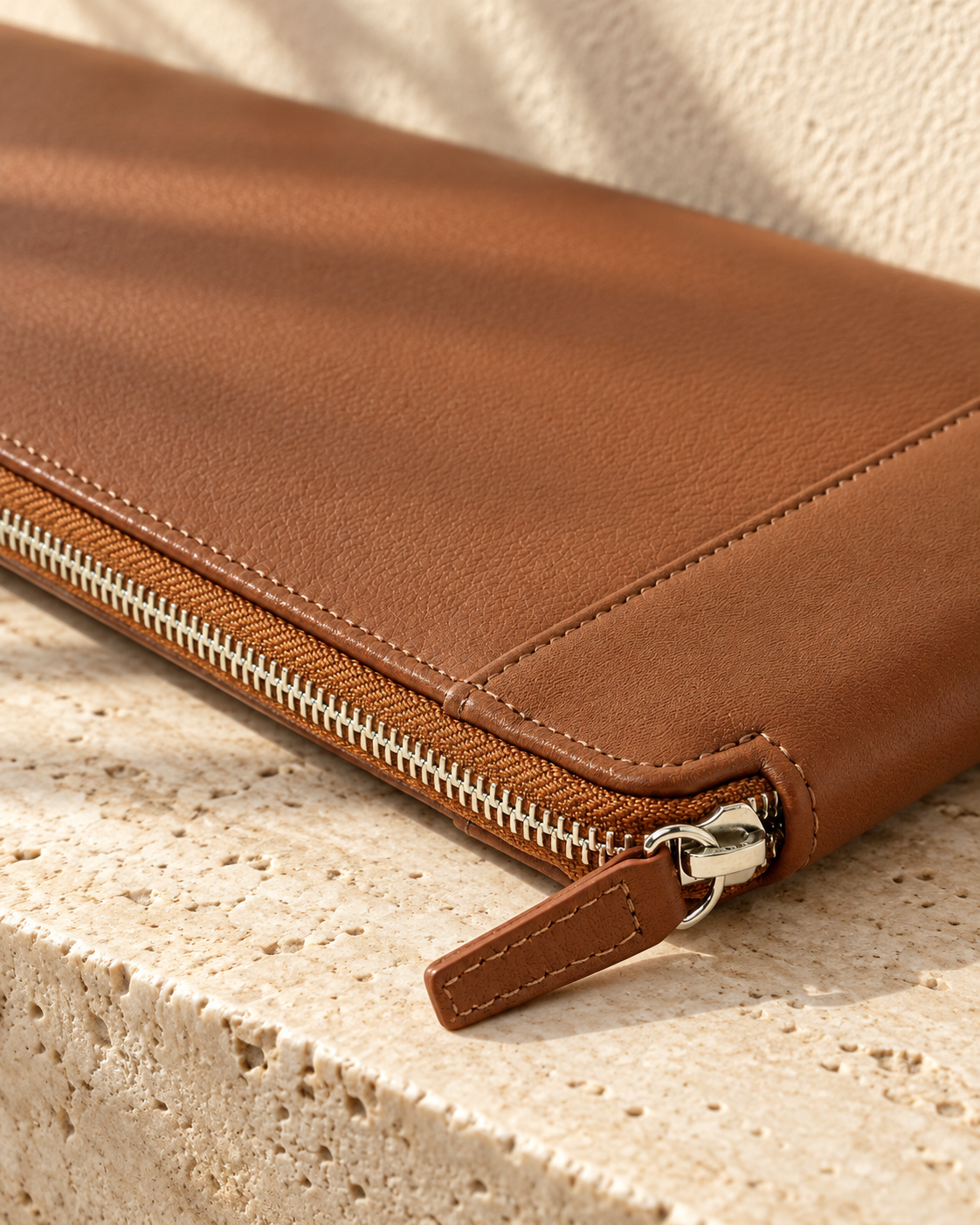 Detail of the illustrative portfolio showing the zip track, slider and pull beside edge stitching and the intersecting spine seam.