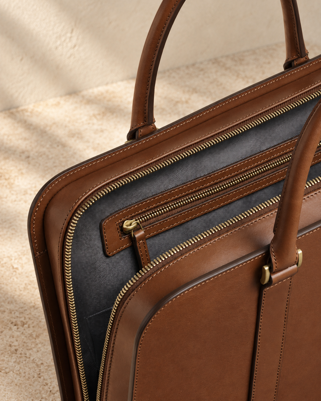 Open detail of the illustrative briefcase showing grey fabric-look lining, a long trimmed wall zip pocket and the main zip at the side.