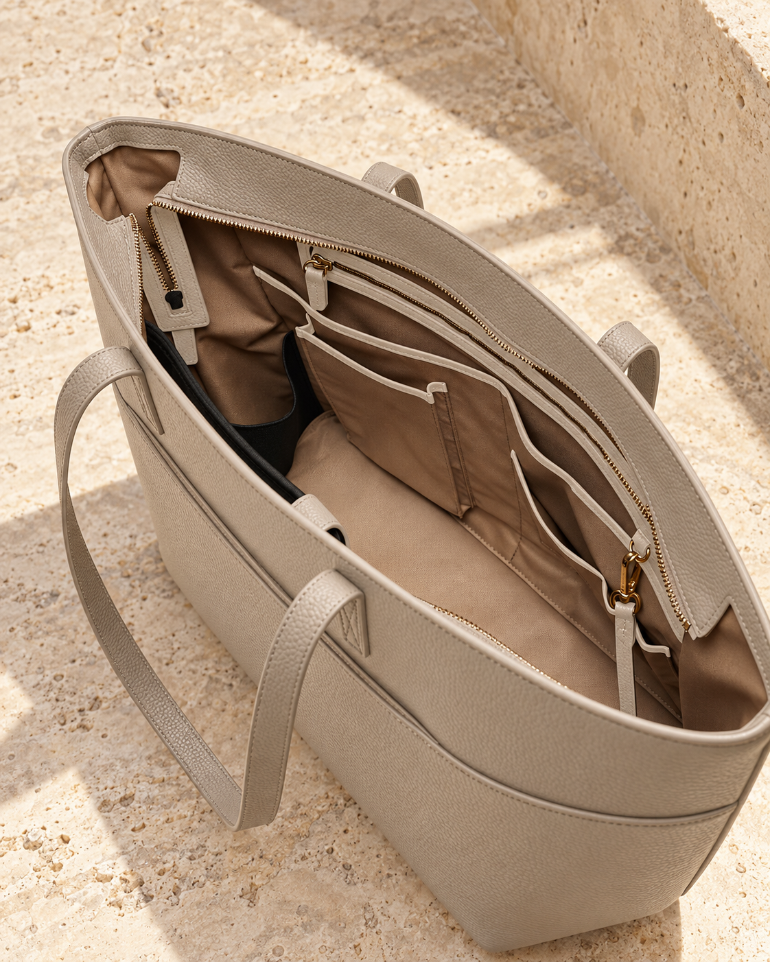 Interior of the illustrative tote showing a recessed zipper bridge, wall zip, open organisers and clip tether.