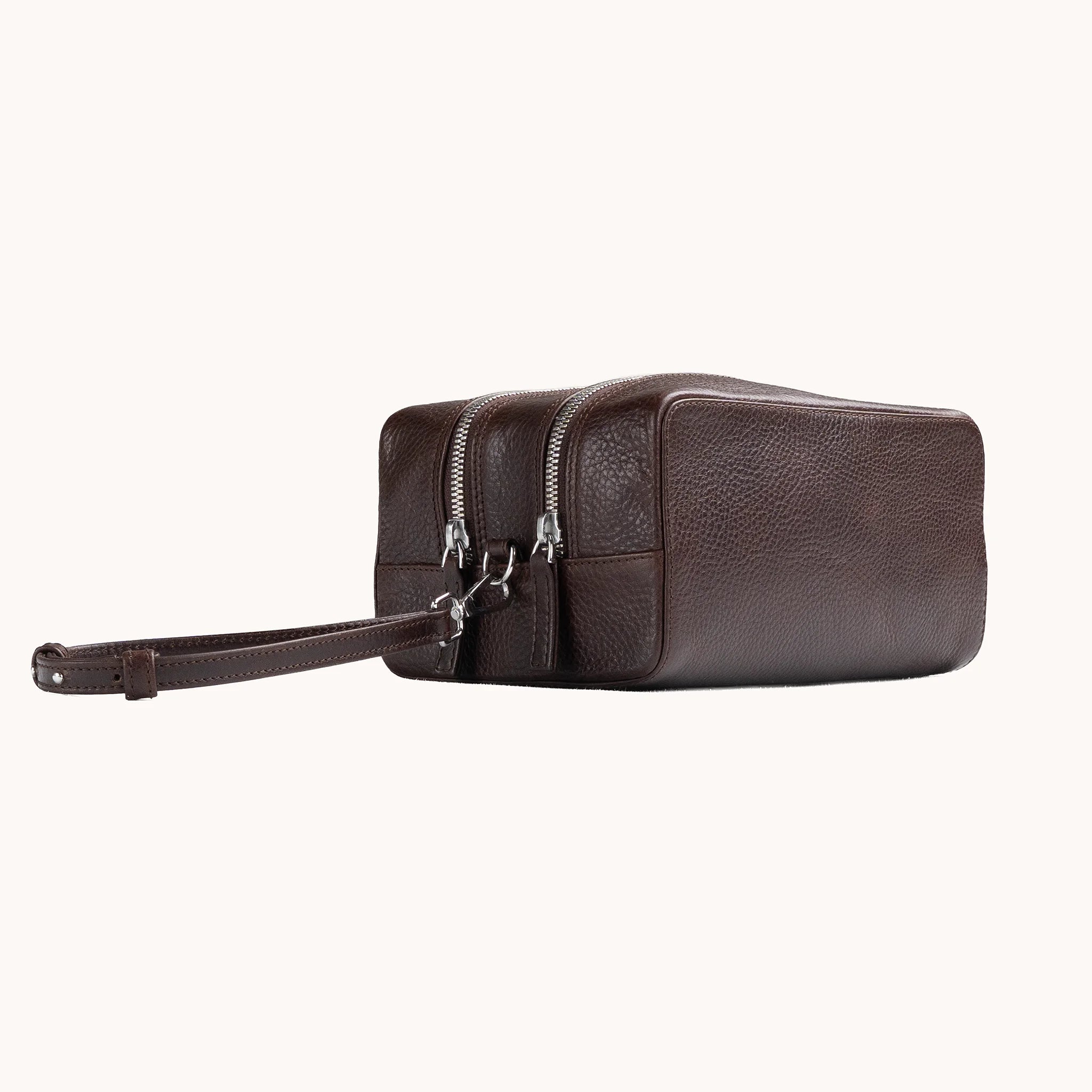 Lunburg Chamberlain Grand Toiletry Bag in tumbled Deep Mahogany leather, three-quarter view showing depth and zip line.