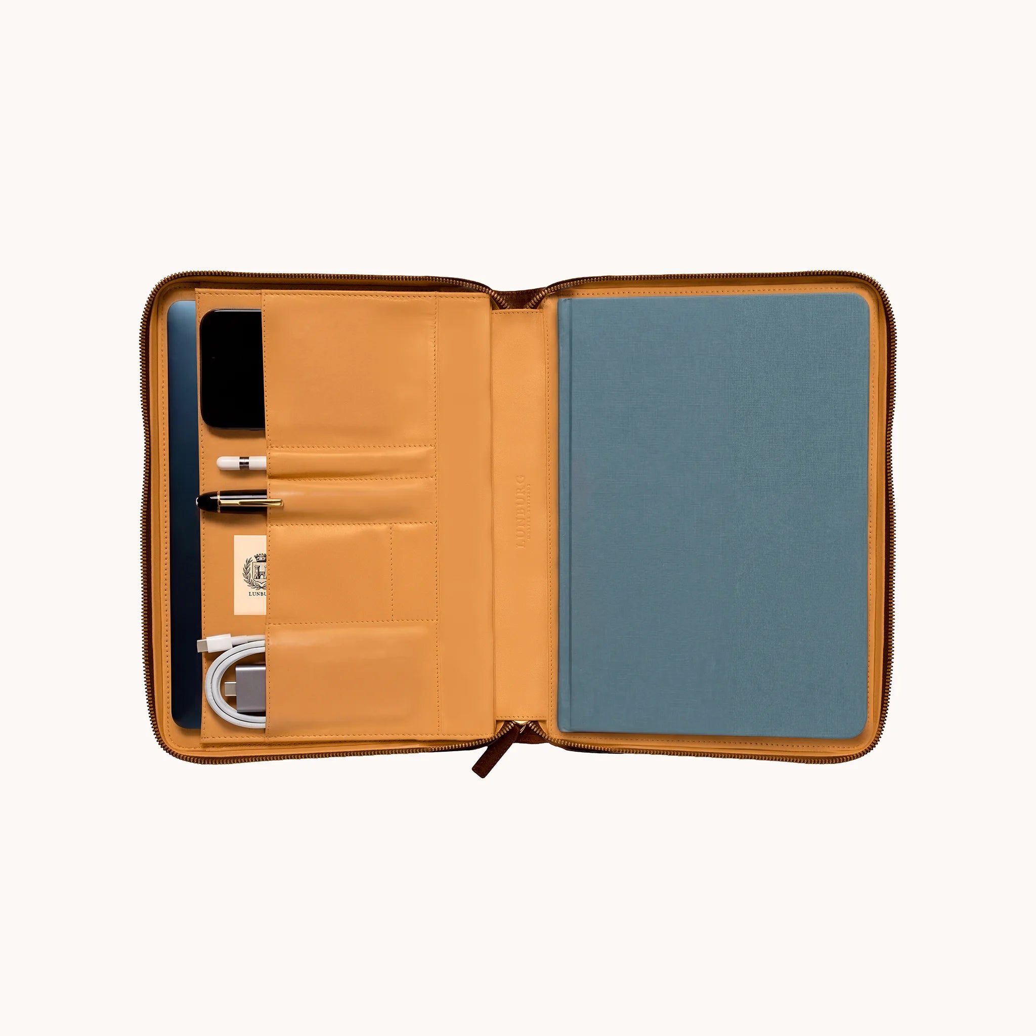 Lunburg Memoir Grand Workstation Portfolio, open interior view styled with a tablet, pen, cable, and notebook, demonstrating the goat leather lining compartments and organisational layout, in vegetable-tanned Perpetual Leather (from Tempesti) with folded edge construction throughout.