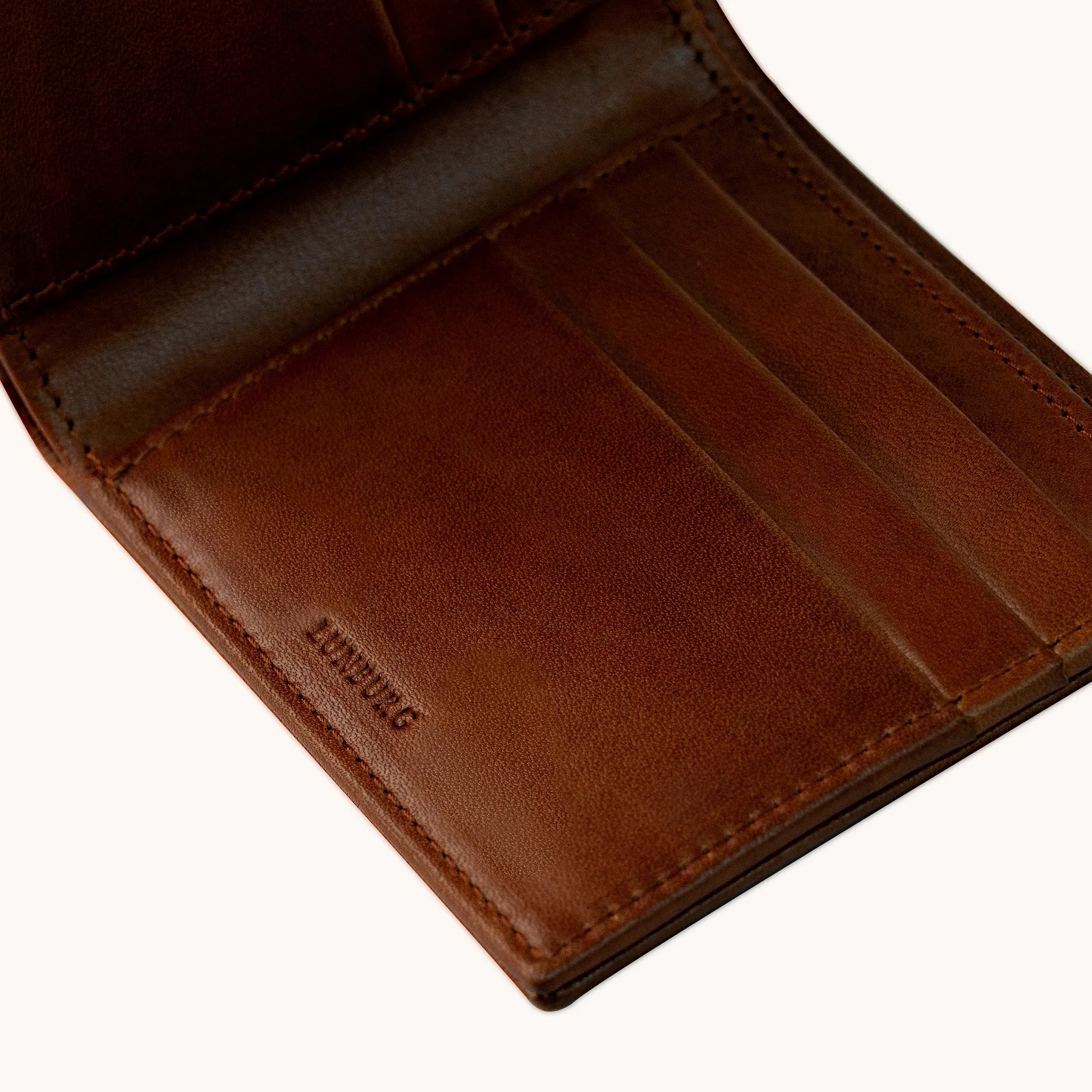 Lunburg Signet Horizontal Bifold in Deep Mahogany, angled interior detail showing the card slot layering, heat-embossed Lunburg mark, and goat leather lining with folded edge construction throughout, in vegetable-tanned Perpetual Leather (from Tempesti).