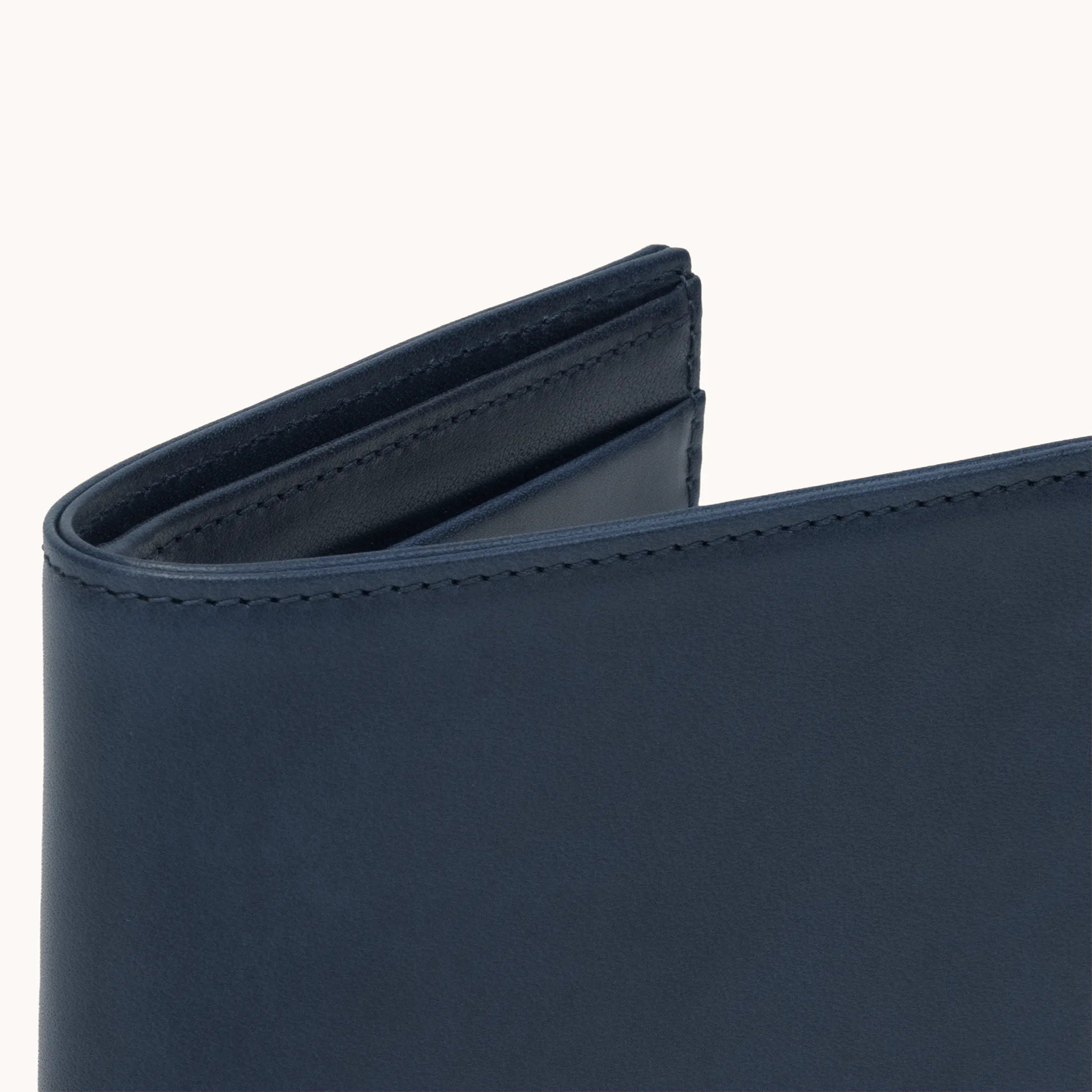 Lunburg Signet Horizontal Bifold in Nocturnal Sapphire, close-up detail of the spine and upper card slot edges showing the folded edge construction of Rempliage where no raw edges are visible, in vegetable-tanned Perpetual Leather (from Tempesti).