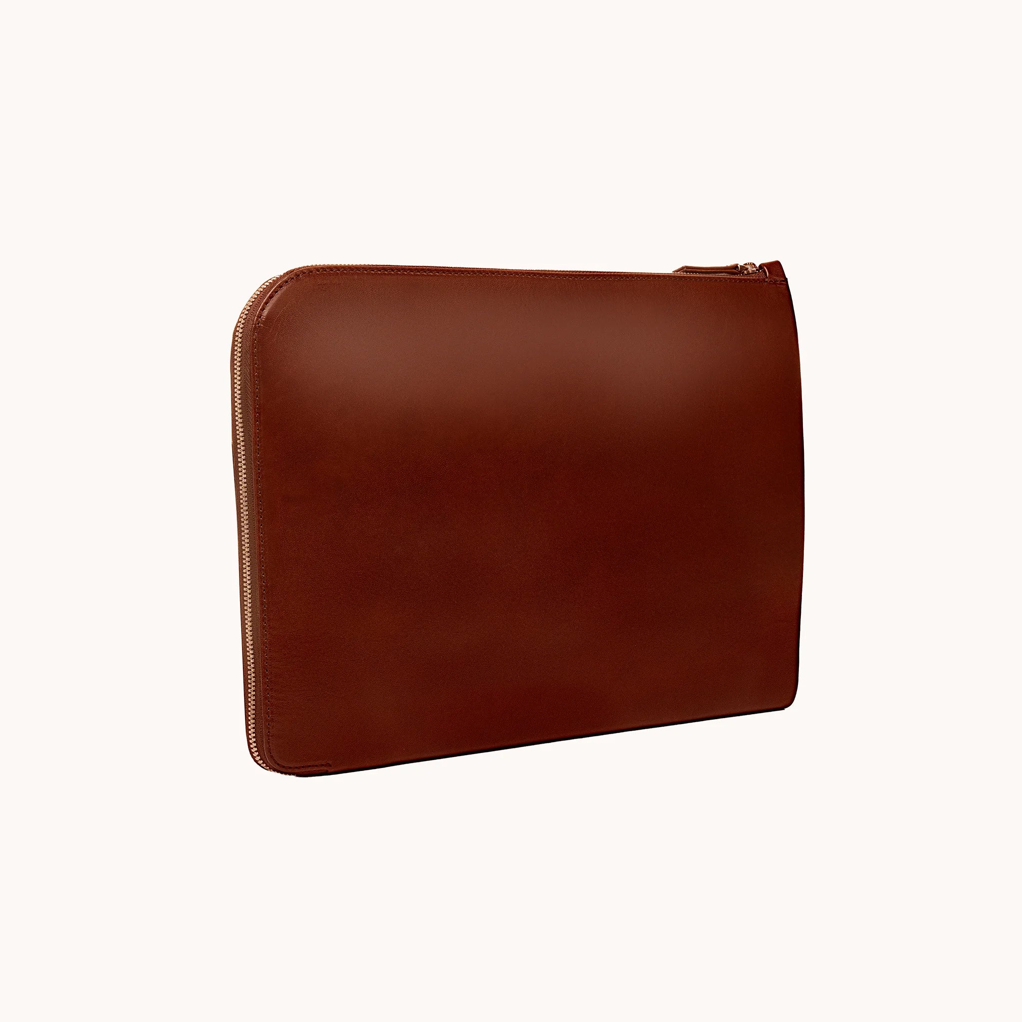 Lunburg Memoir Laptop Sleeve in Deep Mahogany, three-quarter front view showing the clean face, top YKK Excella zipper, and slim profile, in vegetable-tanned Perpetual Leather (from Tempesti) with folded edge construction.