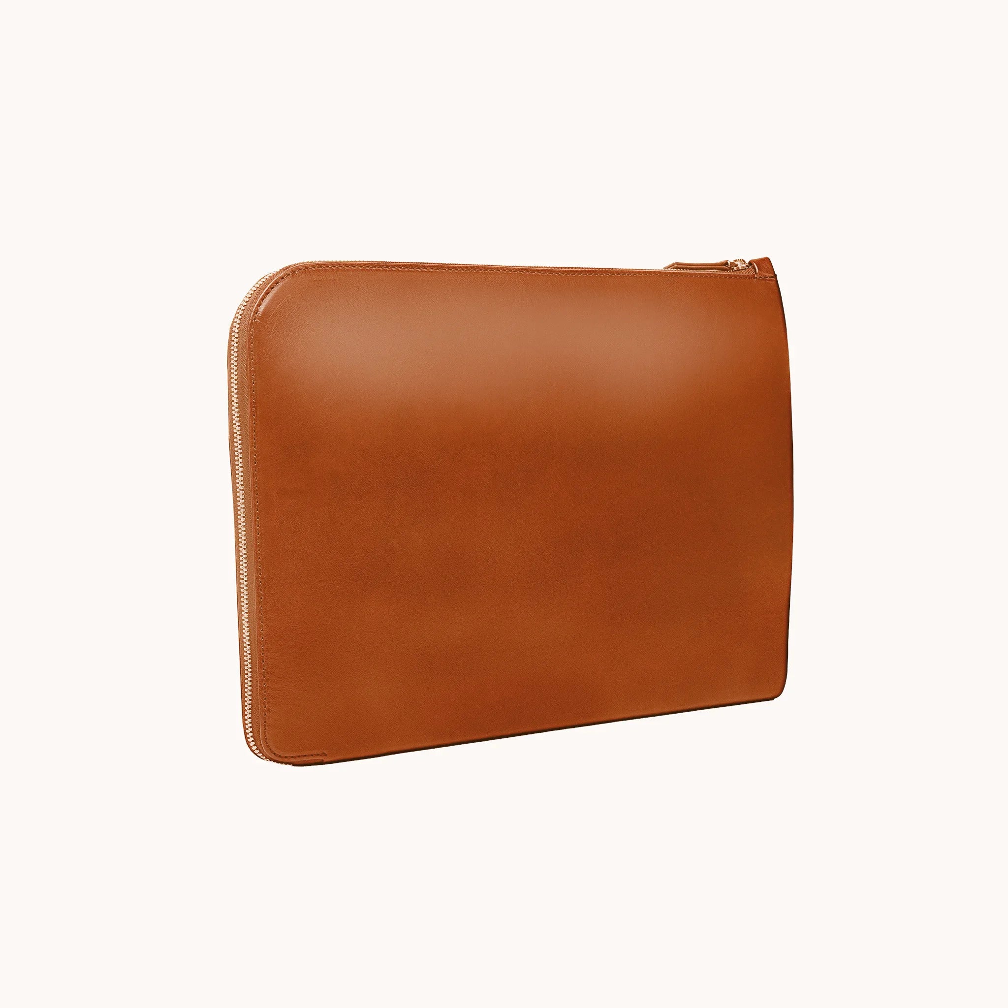 Lunburg Memoir Laptop Sleeve in Heritage Amber, three-quarter front view showing the clean face, top YKK Excella zipper, and slim profile, in vegetable-tanned Perpetual Leather (from Tempesti) with folded edge construction.
