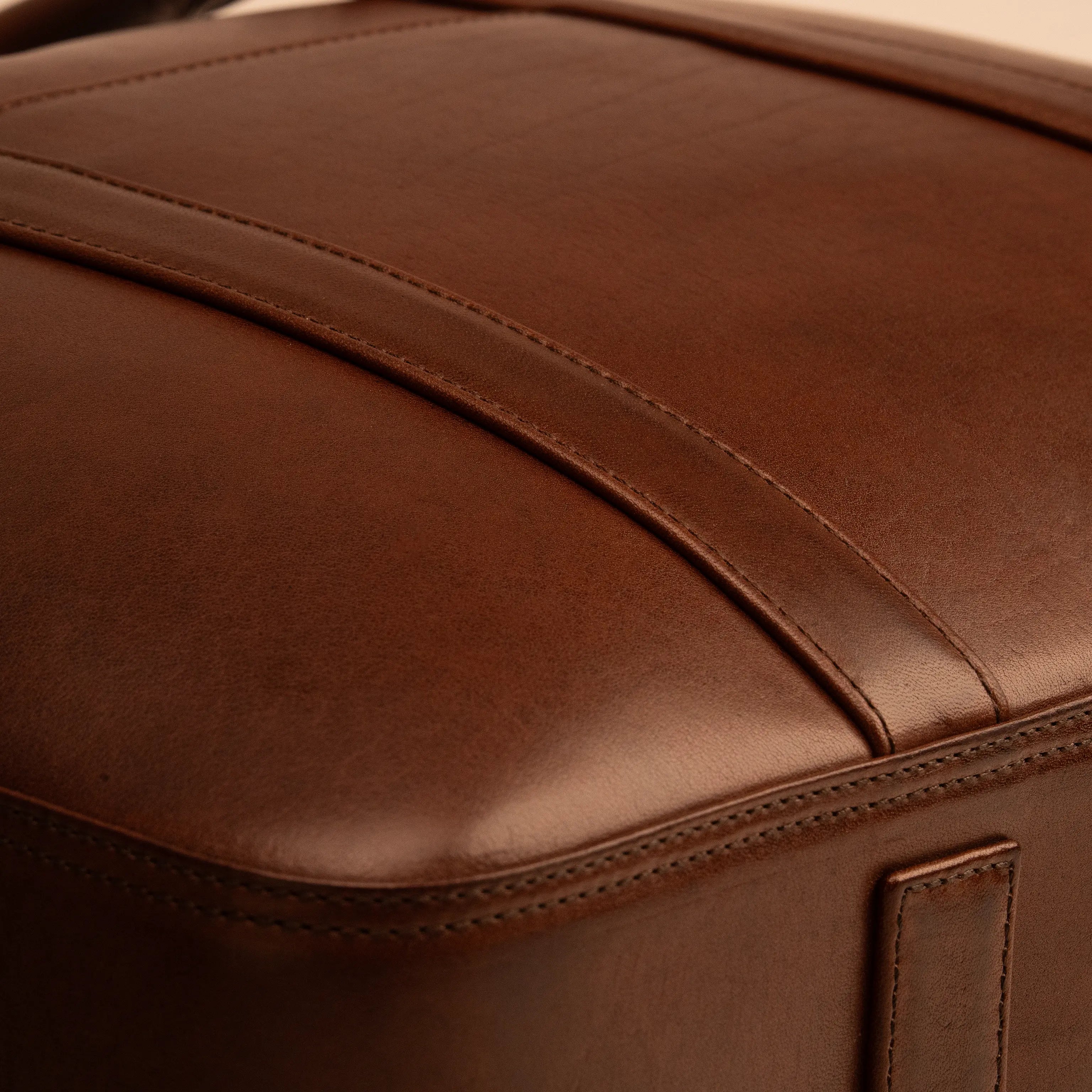 Close-up of the curved panel seam on the Lunburg Opus Briefcase in Deep Mahogany, showing folded edge construction and leather grain in vegetable-tanned Perpetual Leather.