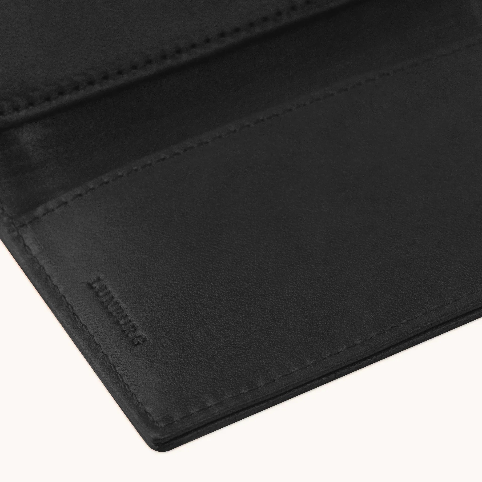 Lunburg Signet Passport Folio in Burnt Timber, detail view of the interior lower panel showing the heat-embossed Lunburg mark beneath card slots, in vegetable-tanned Perpetual Leather (from Tempesti) with folded edge construction throughout.