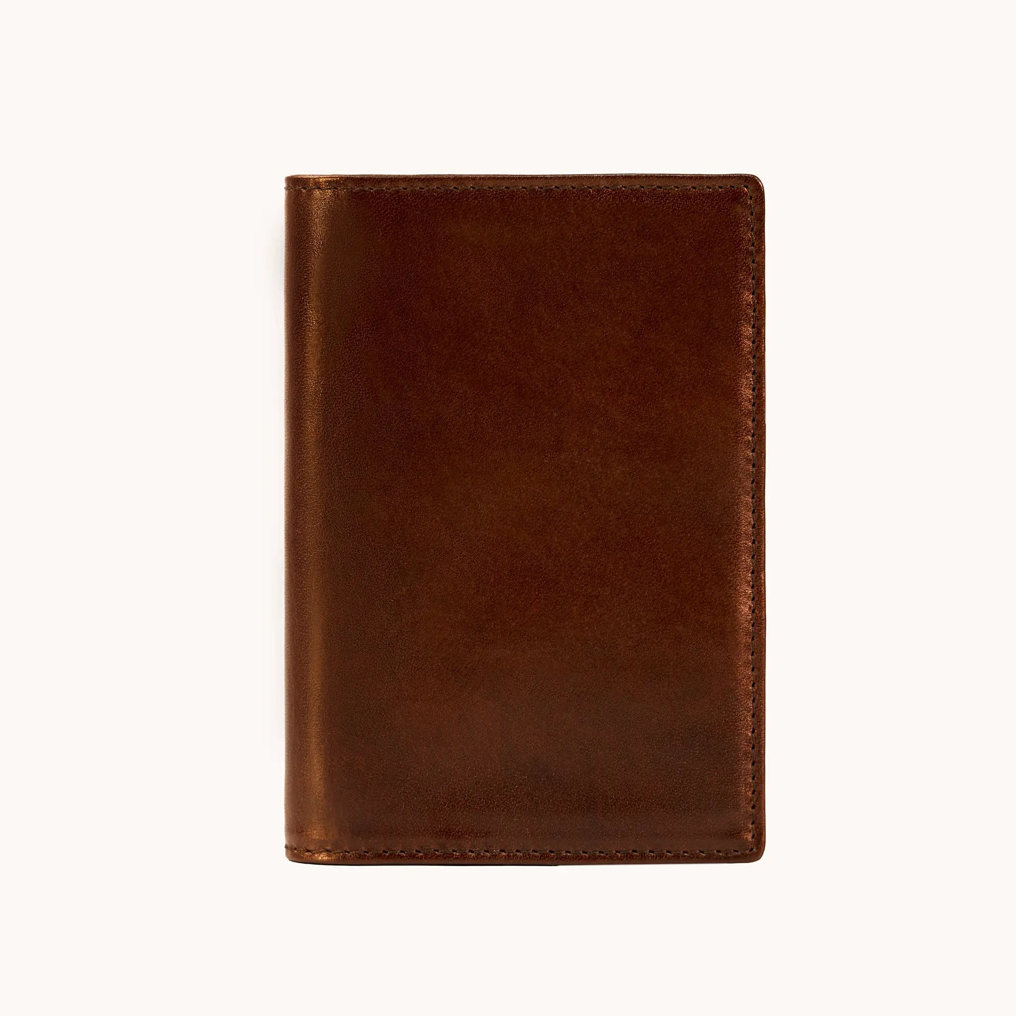 Lunburg Signet Passport Folio in Deep Mahogany, front view closed, showing the clean face of vegetable-tanned Perpetual Leather (from Tempesti) with folded edge construction and no visible raw edges.