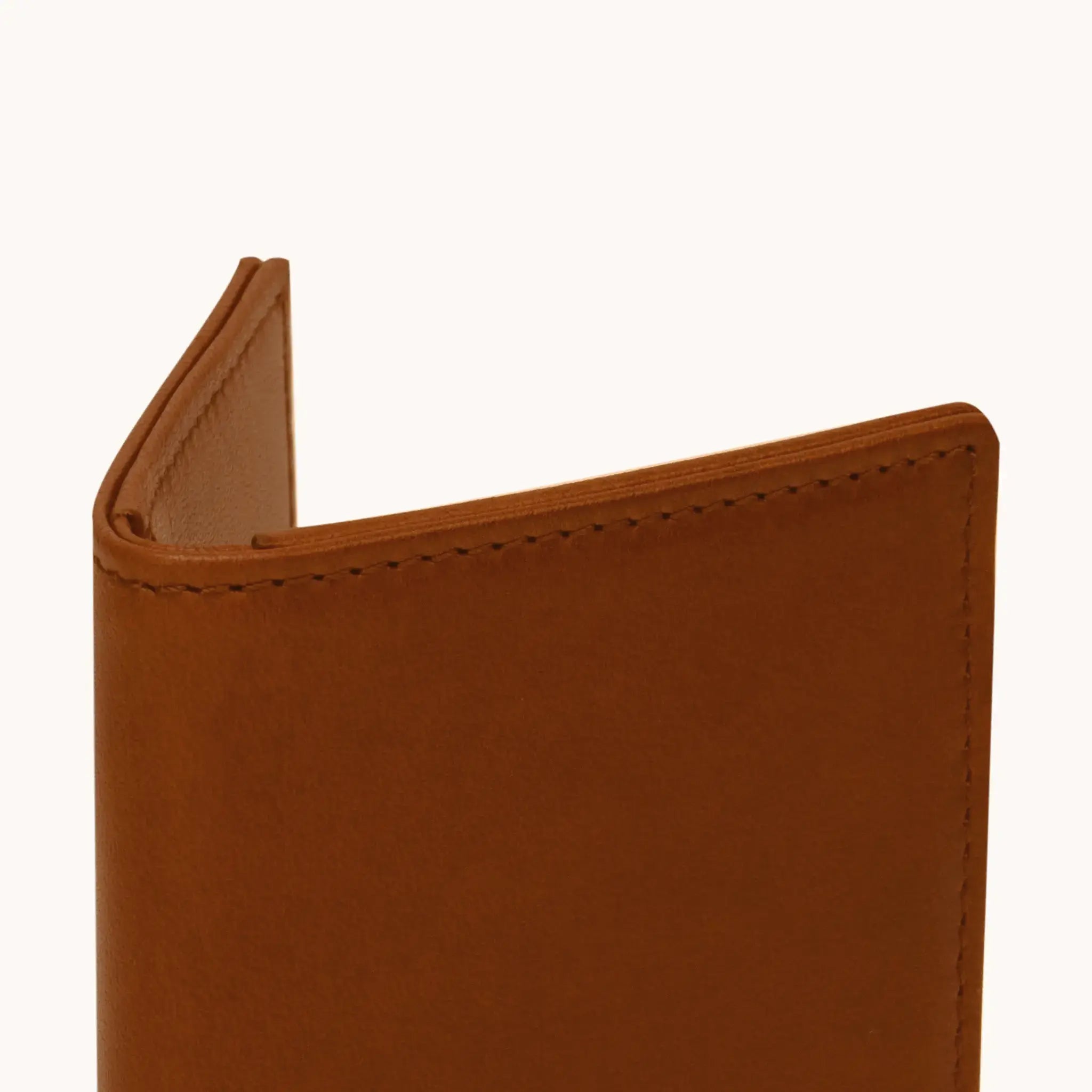 Lunburg Signet Passport Folio in Heritage Amber, close-up detail of the spine and upper edge showing the folded edge construction of Rempliage where no raw edges are visible, in vegetable-tanned Perpetual Leather (from Tempesti).