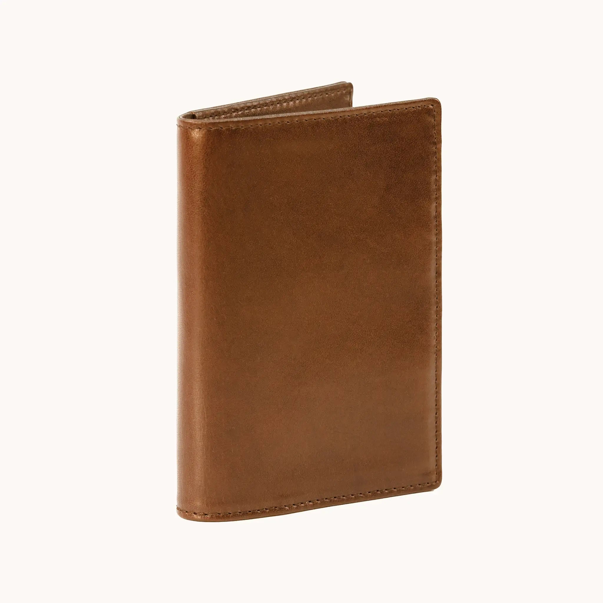 Lunburg Signet Passport Folio in Heritage Amber, three-quarter view slightly open showing the exterior grain, spine, and a glimpse of the interior, in vegetable-tanned Perpetual Leather (from Tempesti) with folded edge construction.