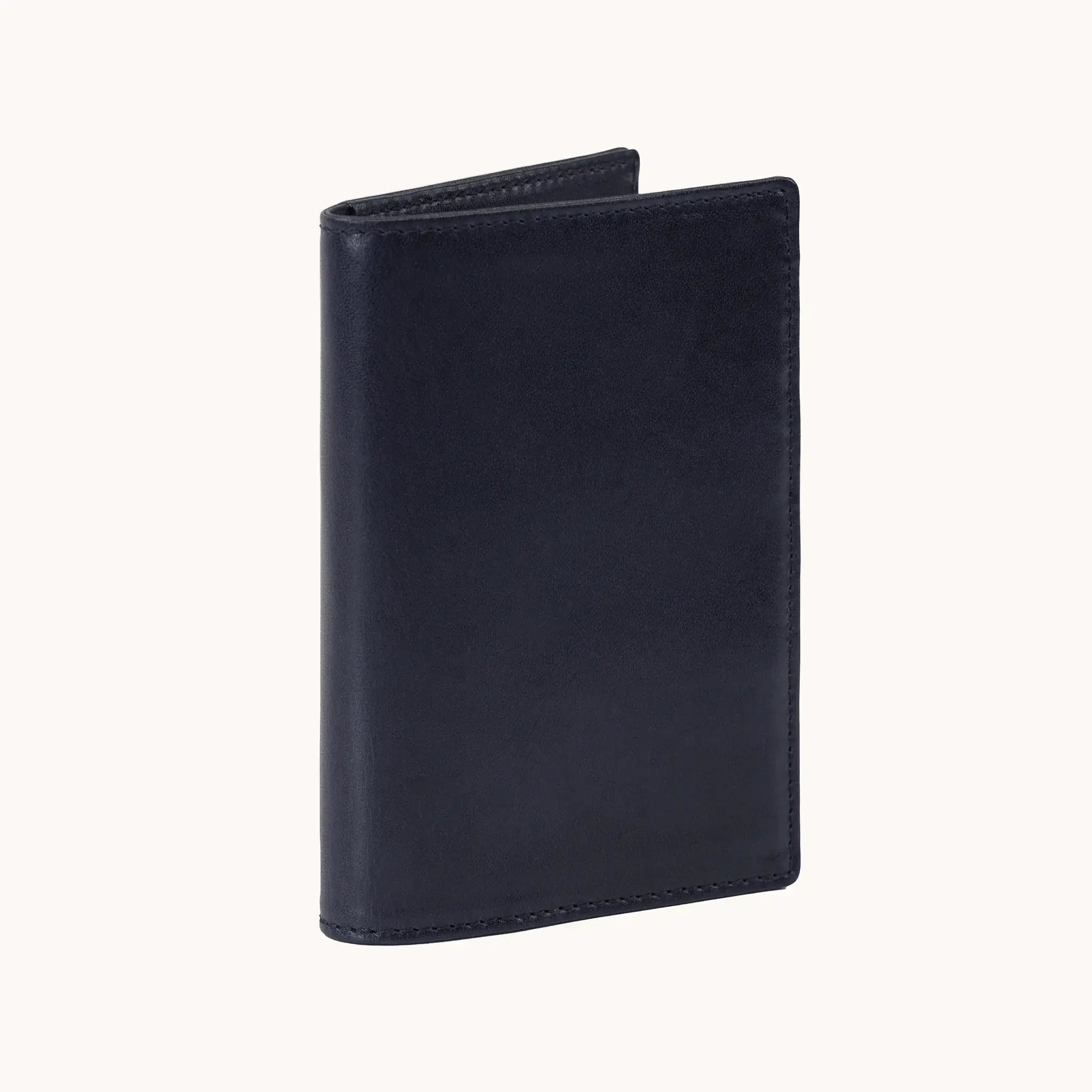 Lunburg Signet Passport Folio in Nocturnal Sapphire, three-quarter view slightly open showing the exterior grain, spine, and a glimpse of the interior, in vegetable-tanned Perpetual Leather (from Tempesti) with folded edge construction.