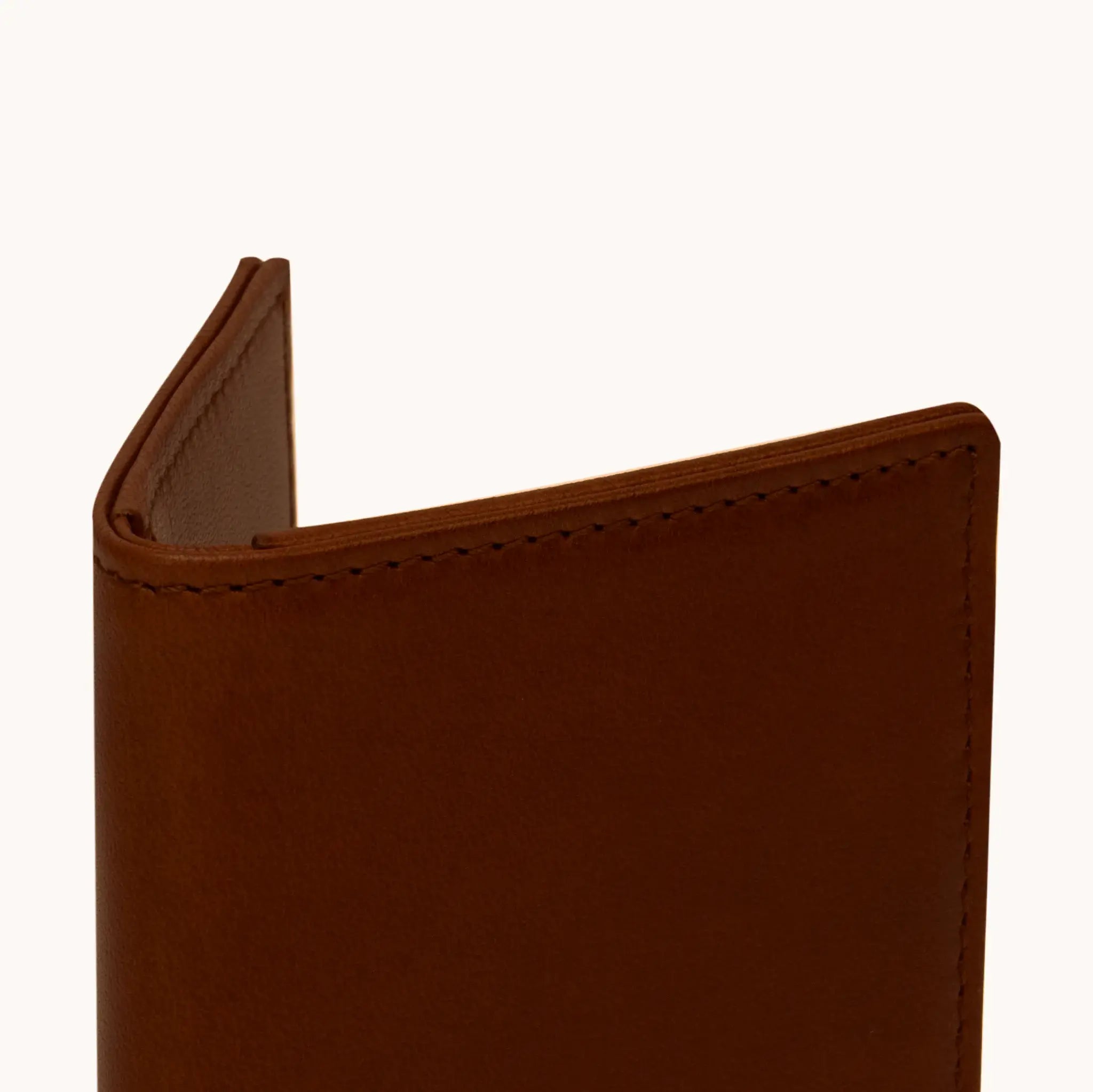 Lunburg Signet Small Vertical in Deep Mahogany, close-up detail of the spine and upper card slot edges showing the folded edge construction of Rempliage where no raw edges are visible, in vegetable-tanned Perpetual Leather (from Tempesti).