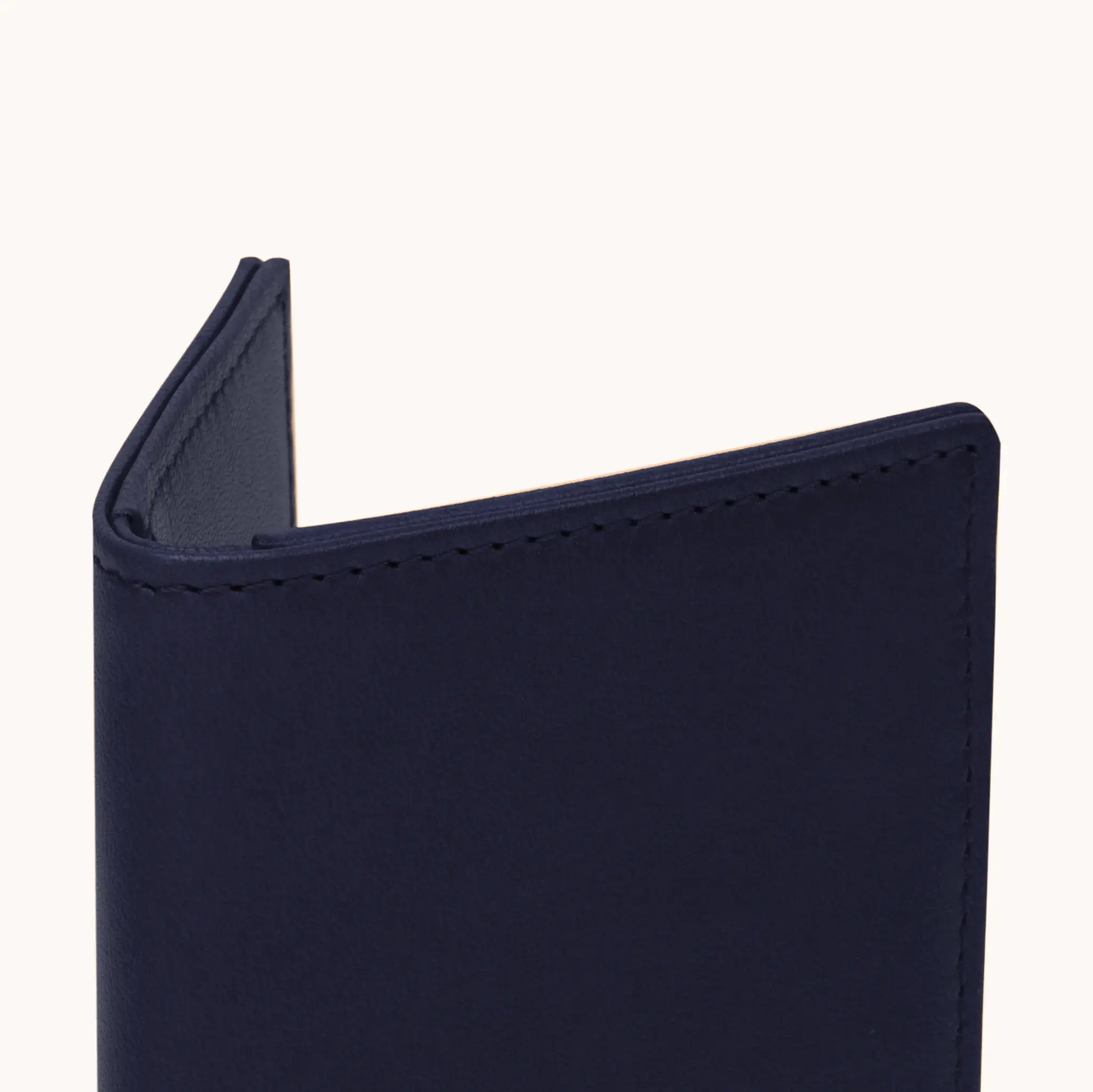 Lunburg Signet Small Vertical in Nocturnal Sapphire, close-up detail of the spine and upper card slot edges showing the folded edge construction of Rempliage where no raw edges are visible, in vegetable-tanned Perpetual Leather (from Tempesti).